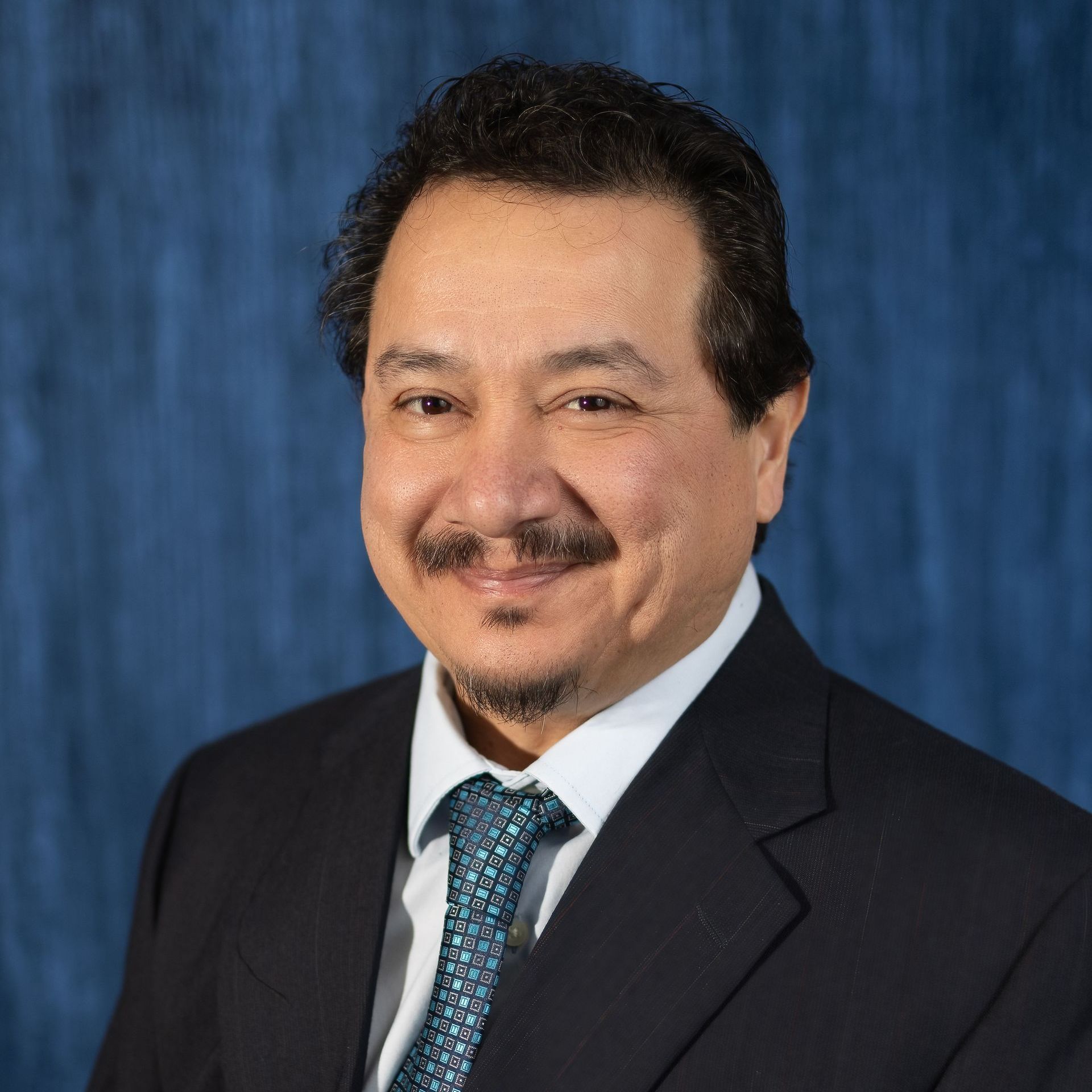 A man in a suit and tie is smiling for the camera.