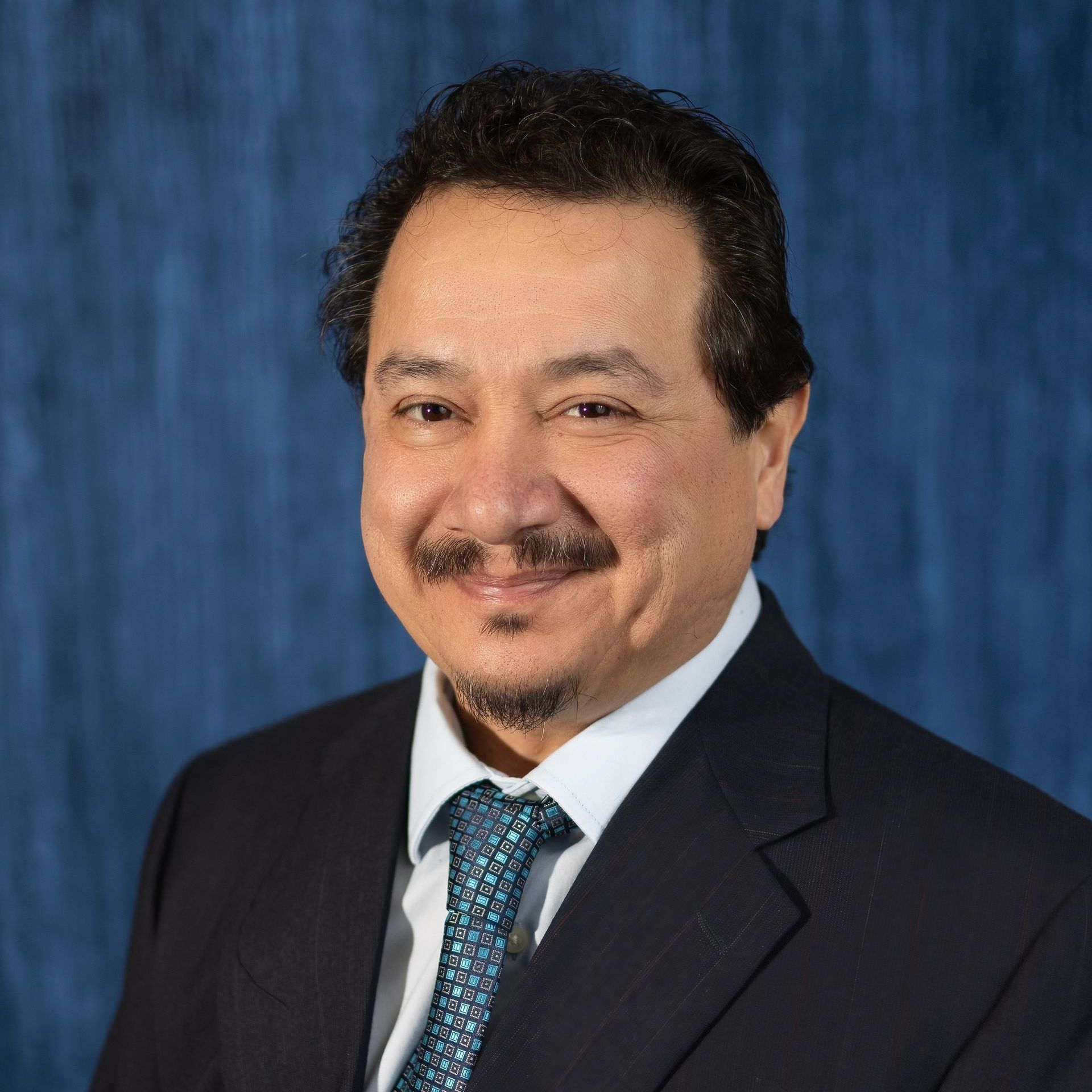 A man in a suit and tie is smiling for the camera.
