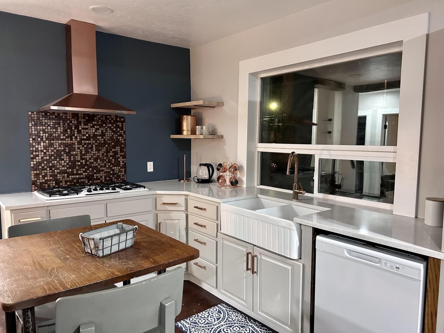 A kitchen with a stove , sink , dishwasher , table and chairs.