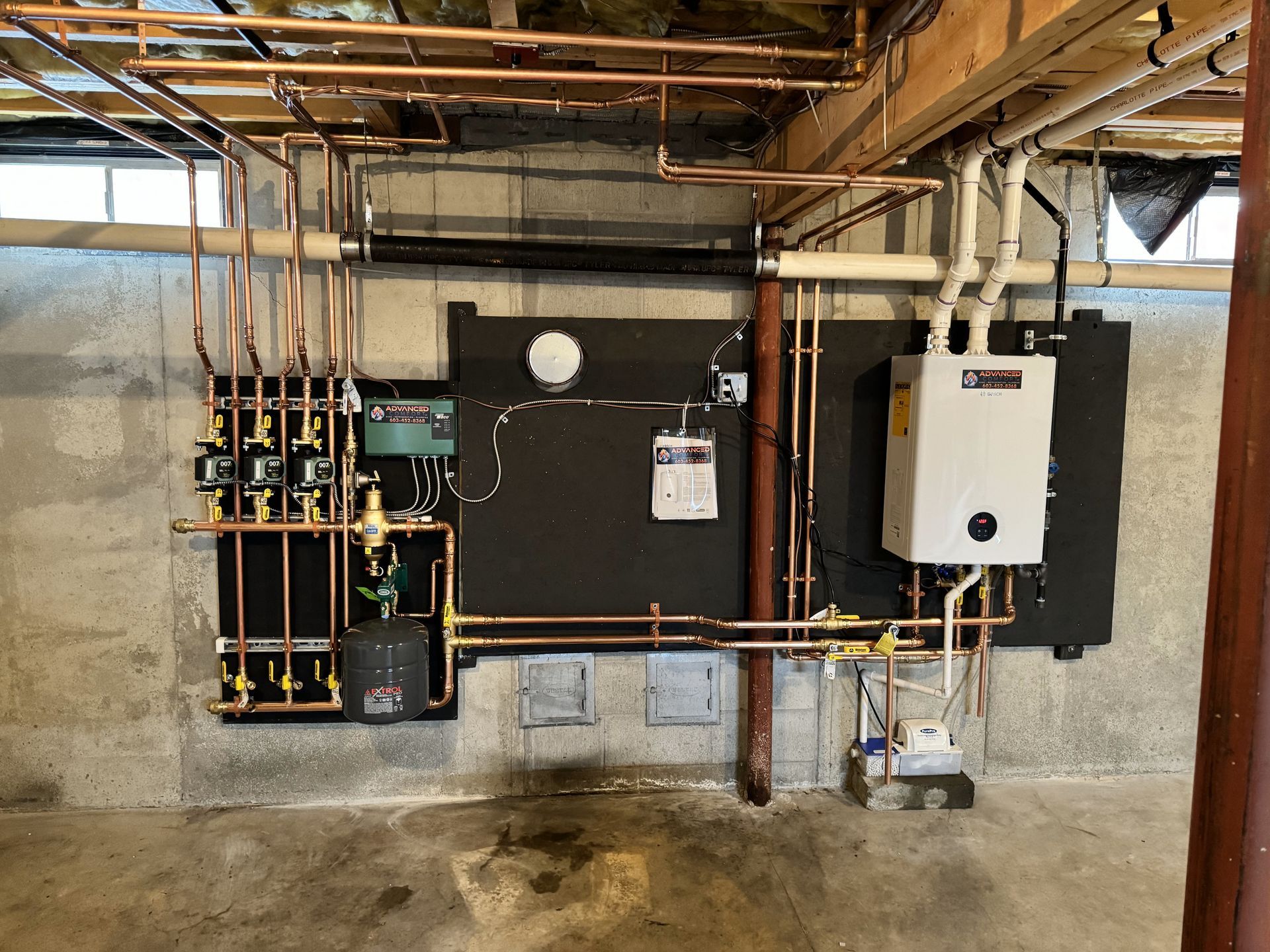 A basement with a lot of pipes and a boiler on the wall.
