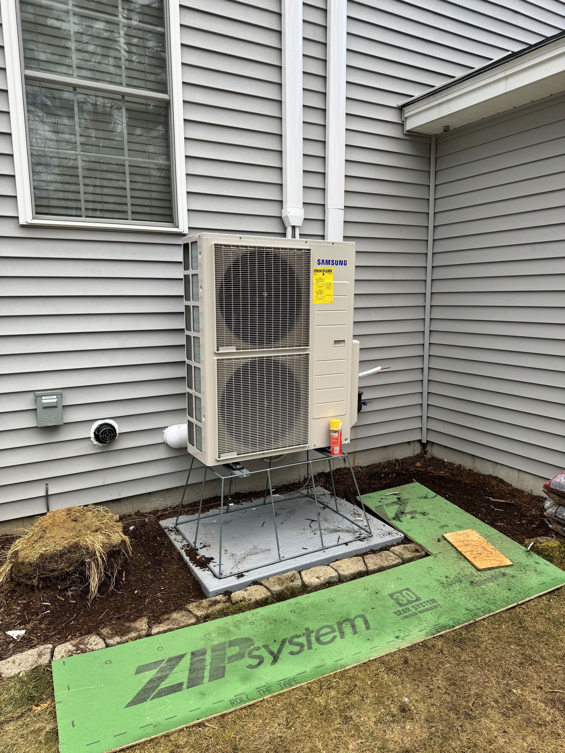 A large air conditioner is sitting on the side of a house.