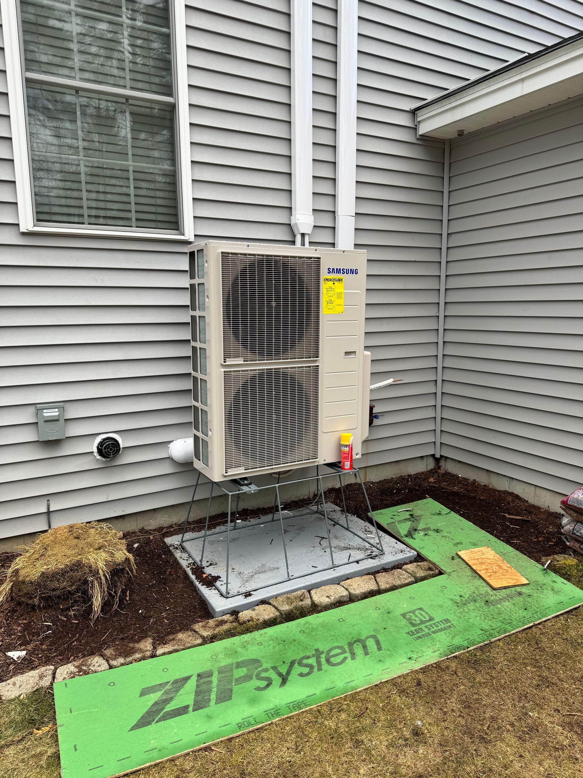 A large air conditioner is sitting on the side of a house.