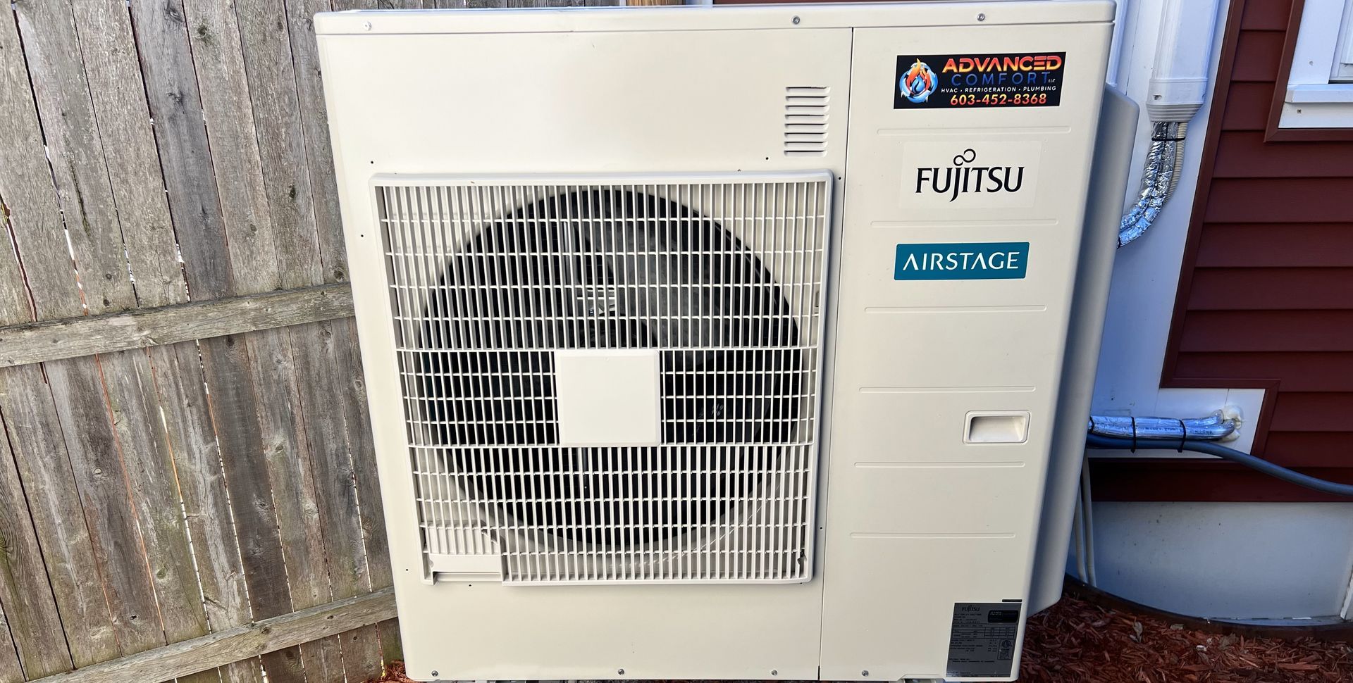 A large white air conditioner is sitting on the side of a building.