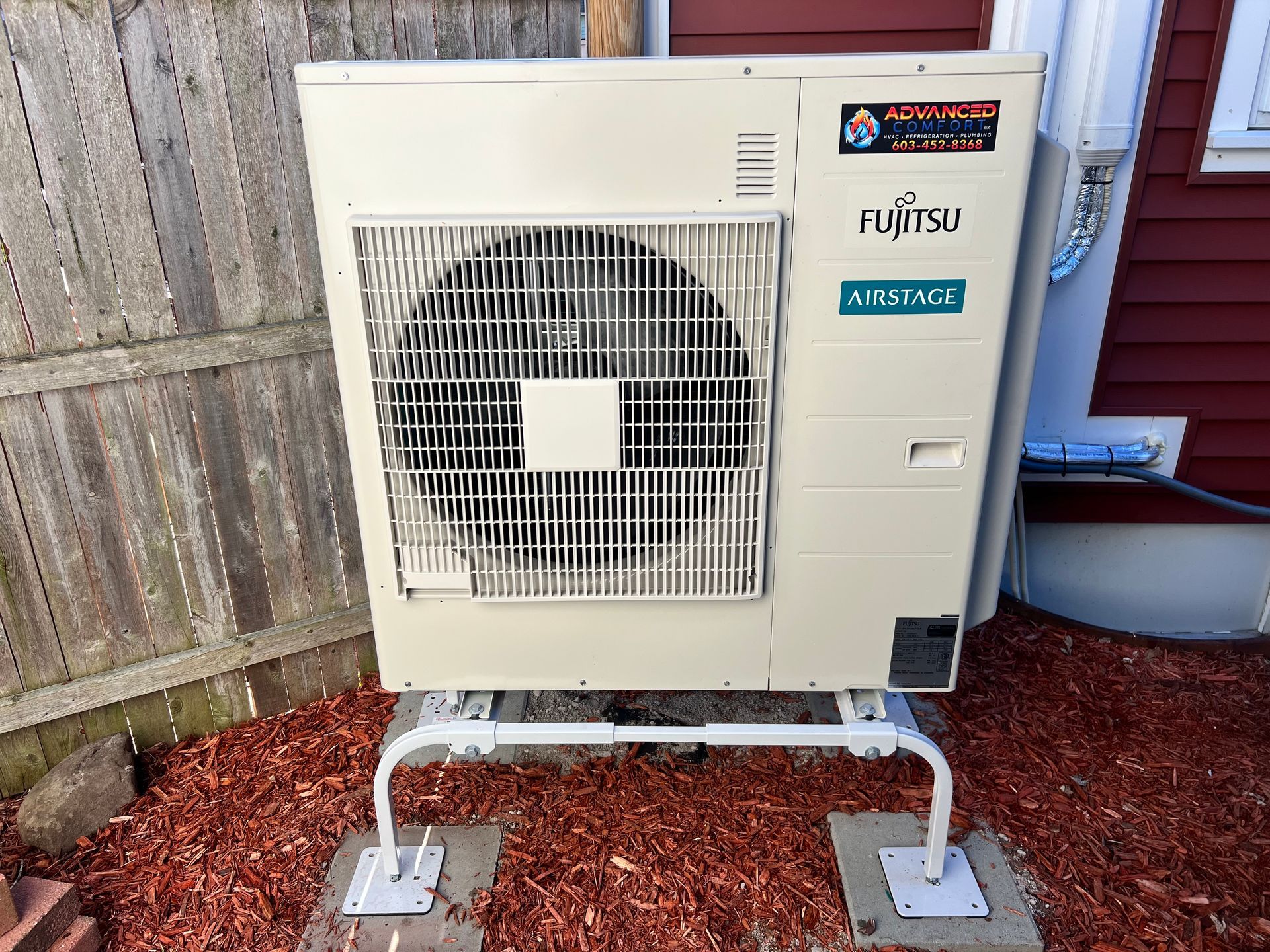 A fujitsu air conditioner is sitting outside of a house.
