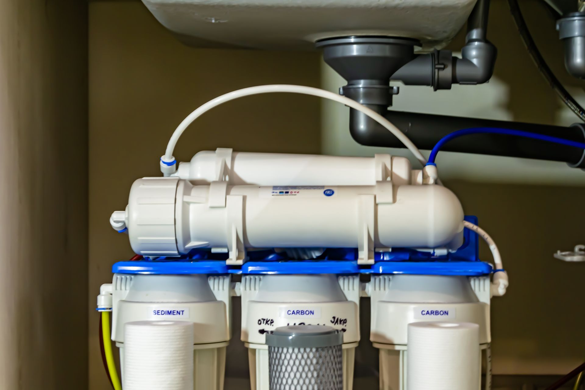 A water filter is under a sink in a kitchen.