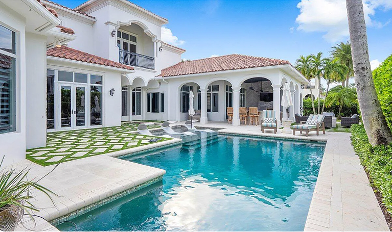 Luxury white villa with red tile roof and turquoise pool in a sunny courtyard