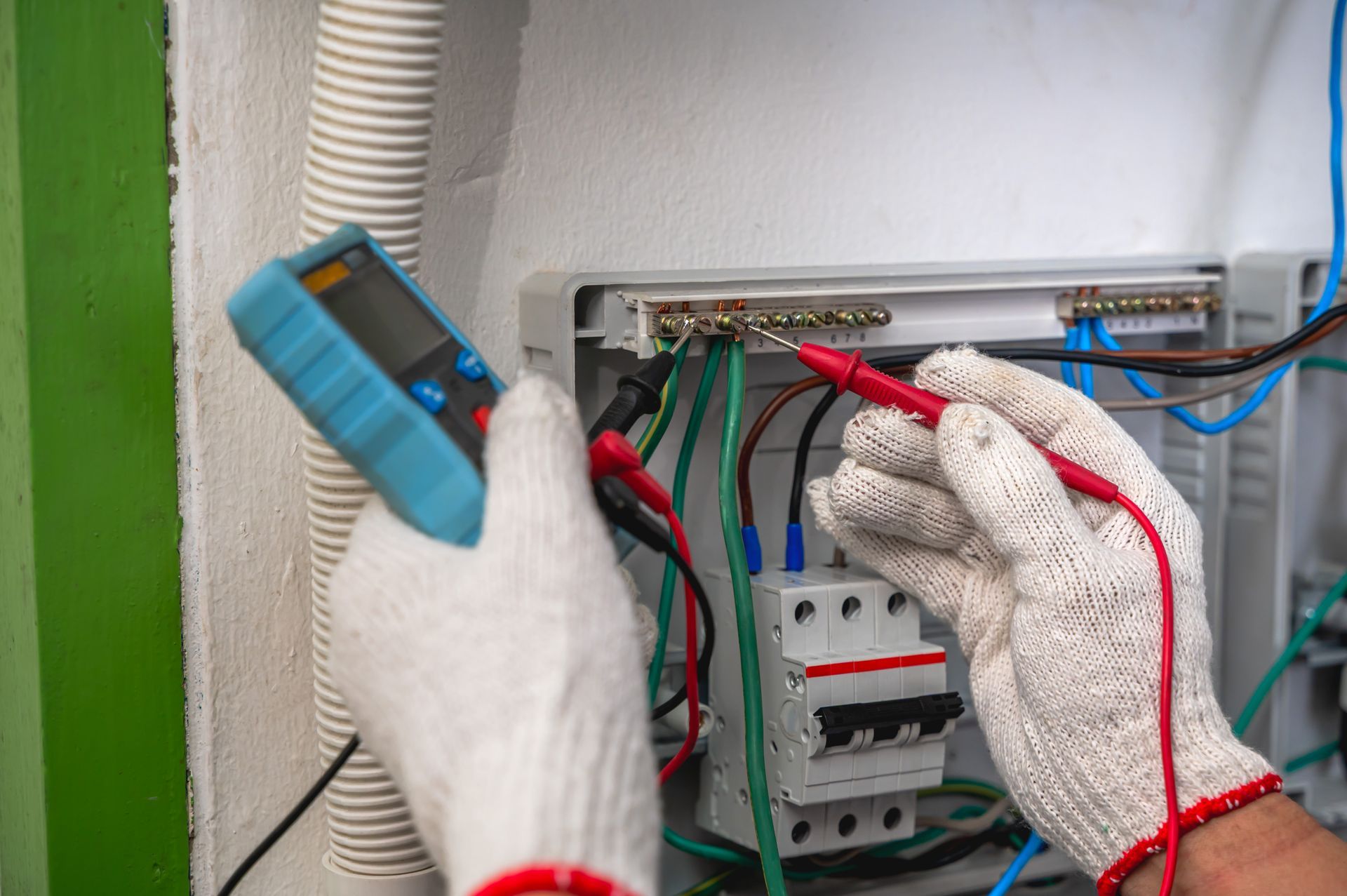 Technician using a multimeter for electrical repair and diagnostic testing on a breaker panel.