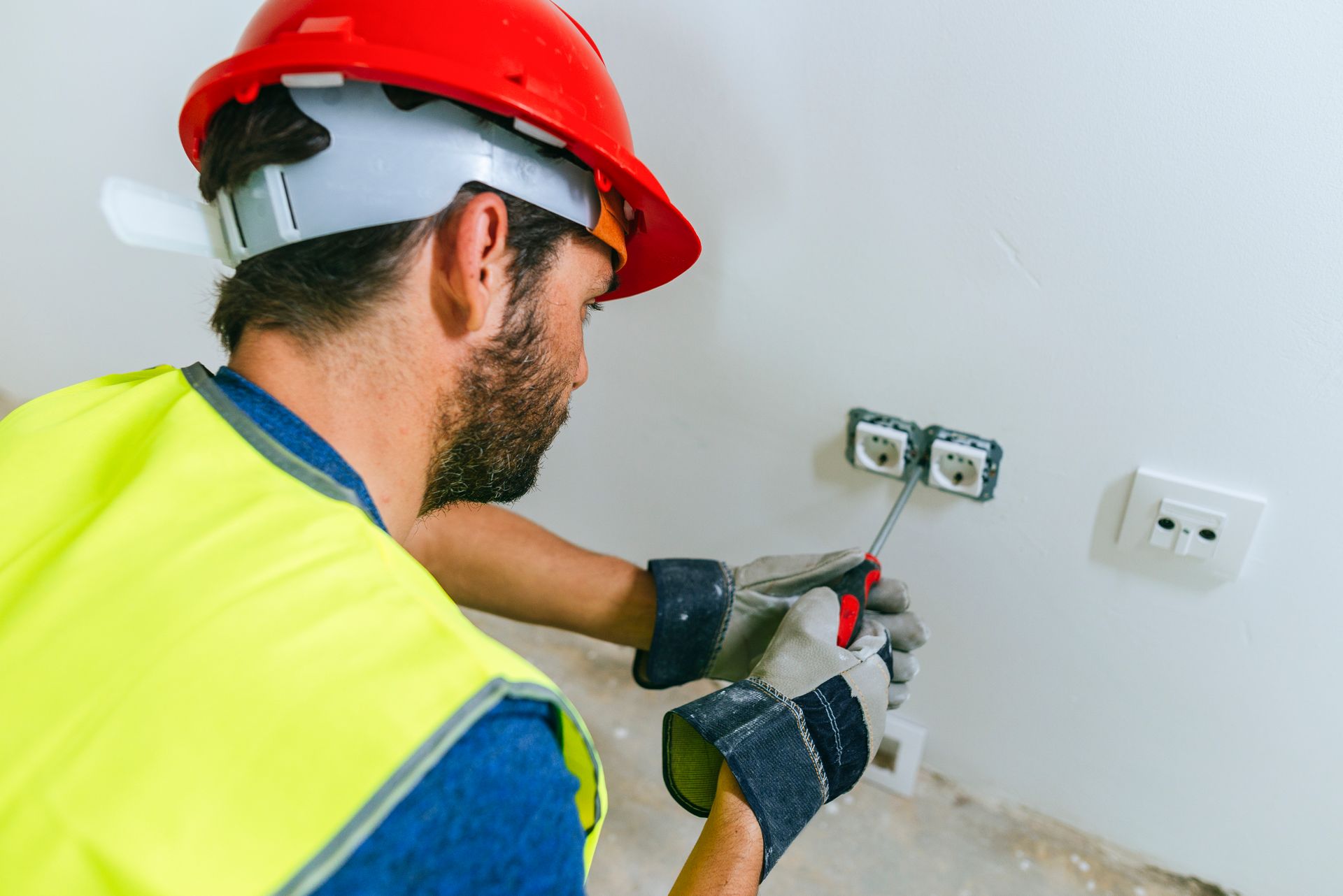 Electrician Fixing Electrical Outlet Wearing Safety Vest
