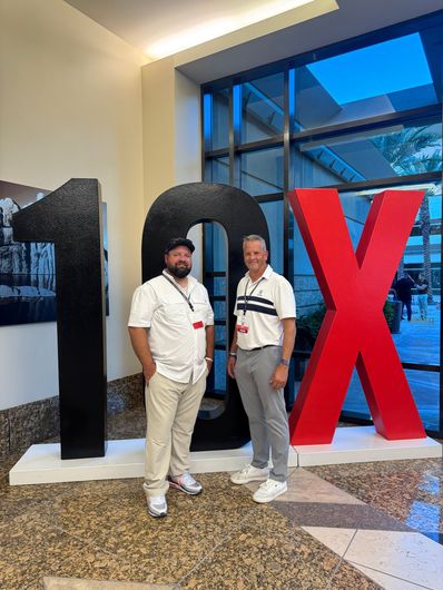 Two people standing beside large black and red display letters in a modern indoor lobby