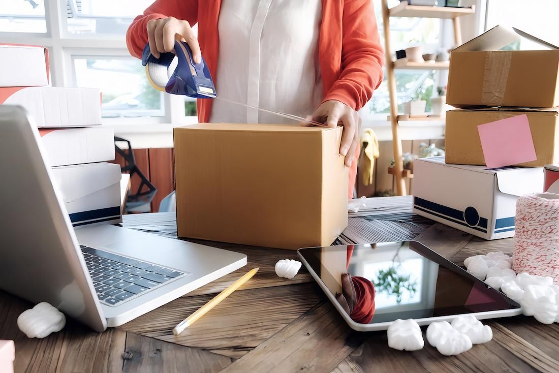 A Woman is Packing a Box on a Wooden Table — Dunford Removals in Miriam Vale, QLD