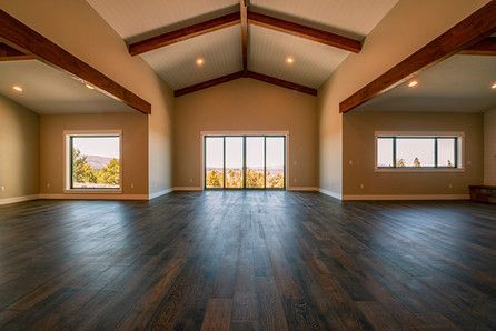 A large empty room with hardwood floors and a vaulted ceiling