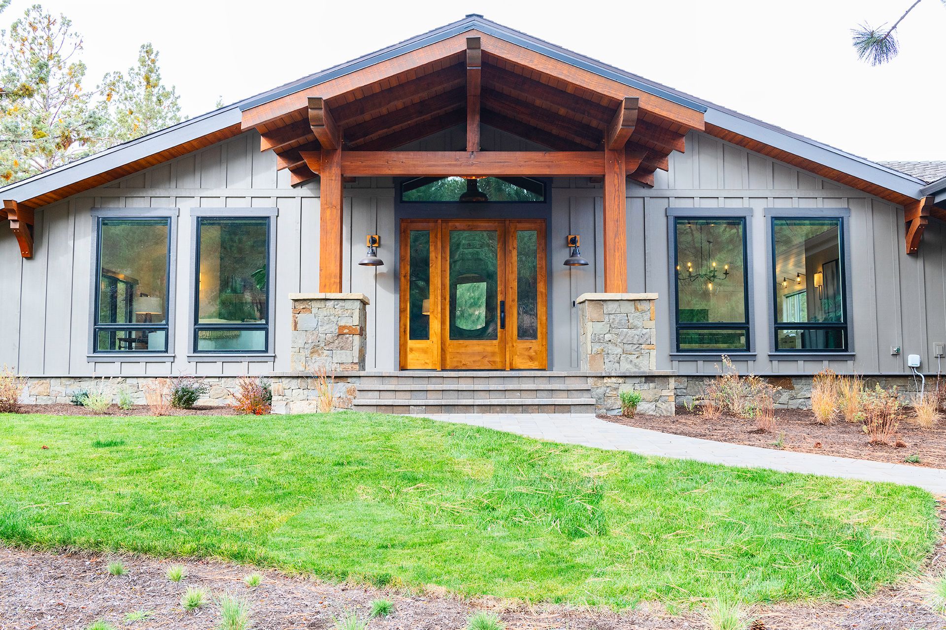 A large house with a lot of windows and a wooden door is sitting on top of a lush green lawn.
