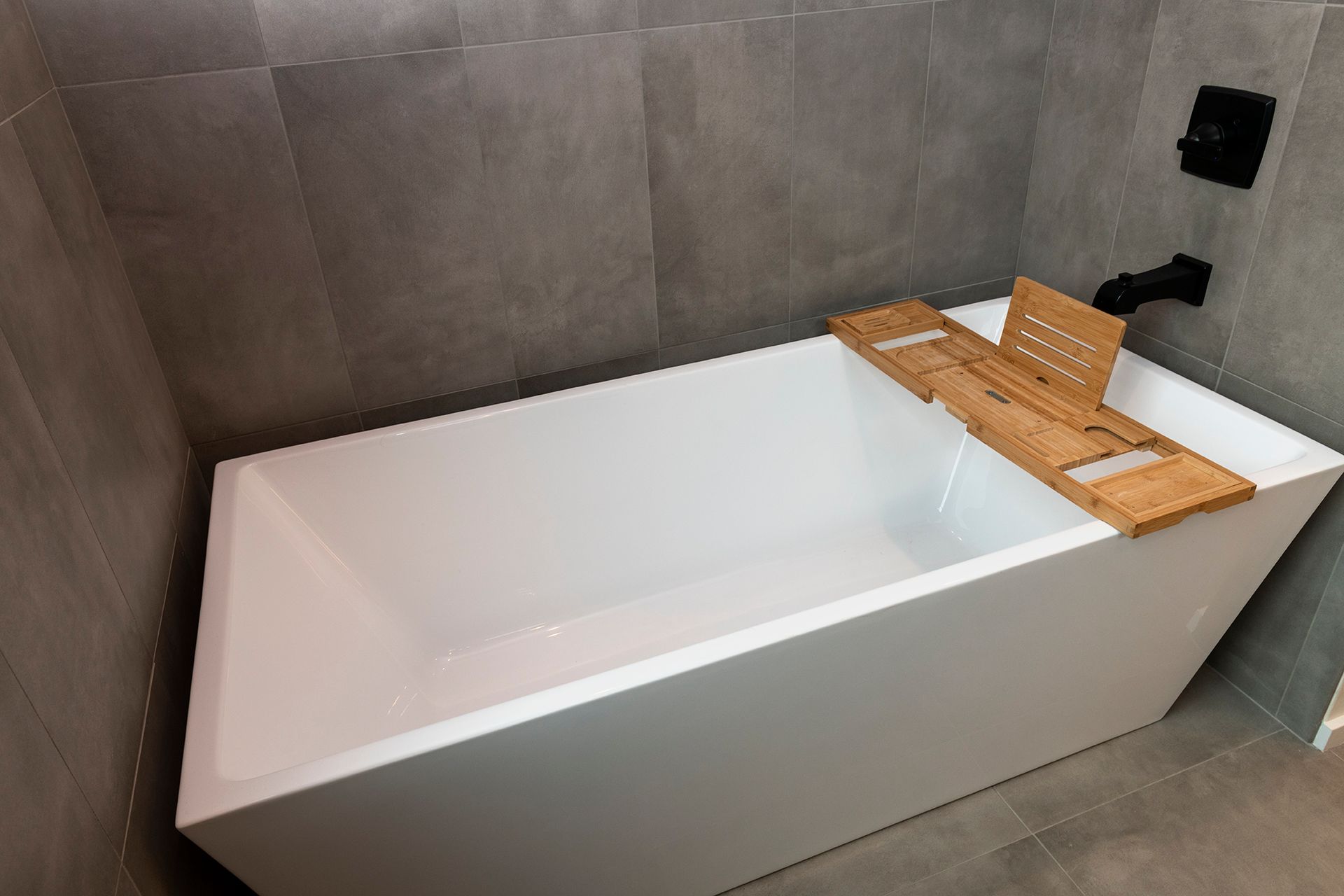A bathtub with a wooden tray on top of it in a bathroom.