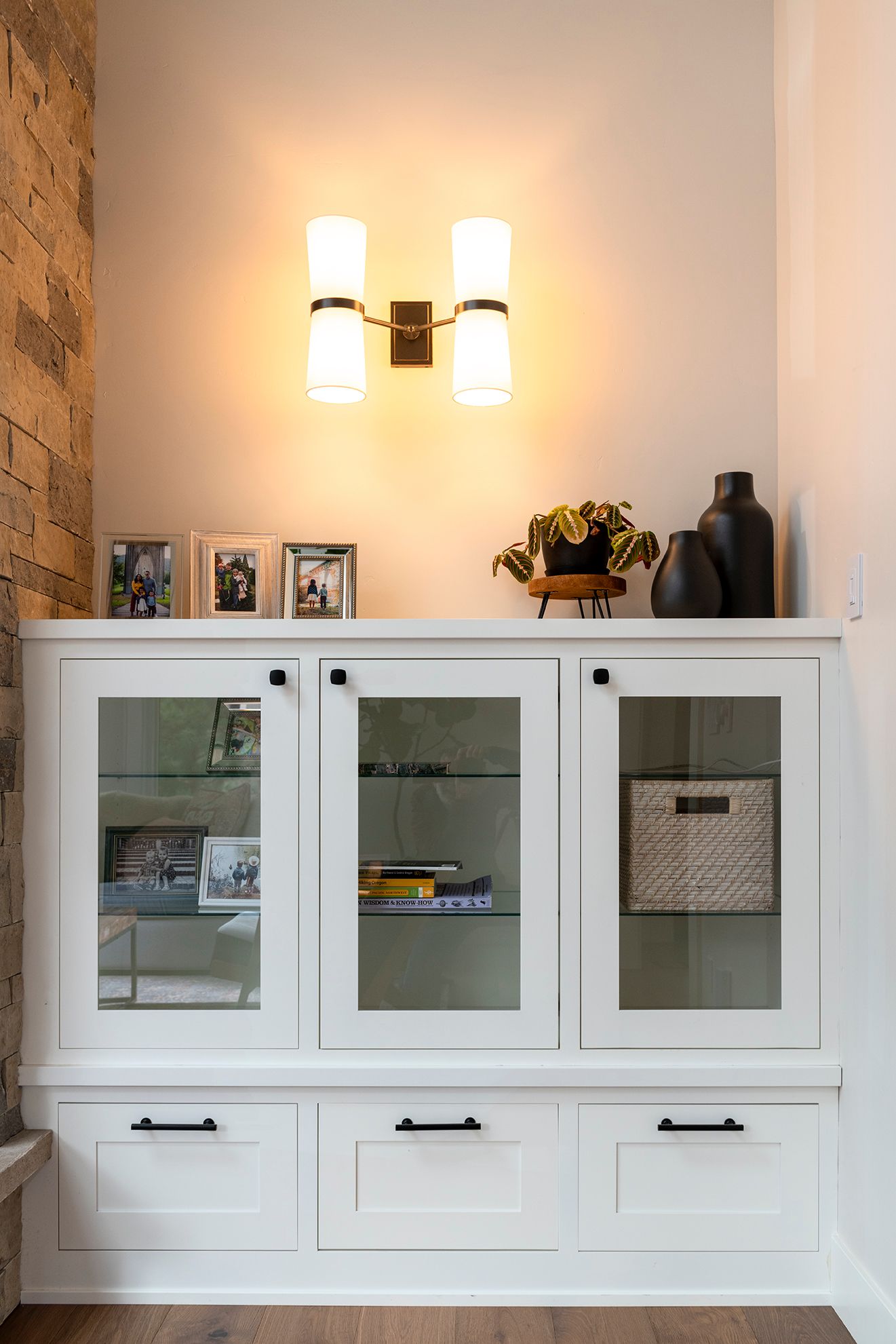 A white cabinet with glass doors and drawers in a living room.