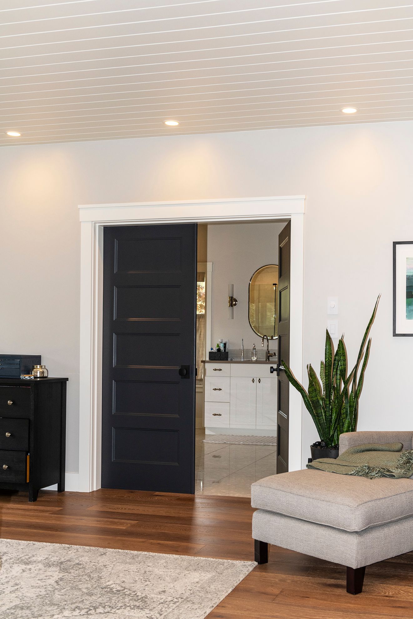 A living room with a black door leading to a bathroom.