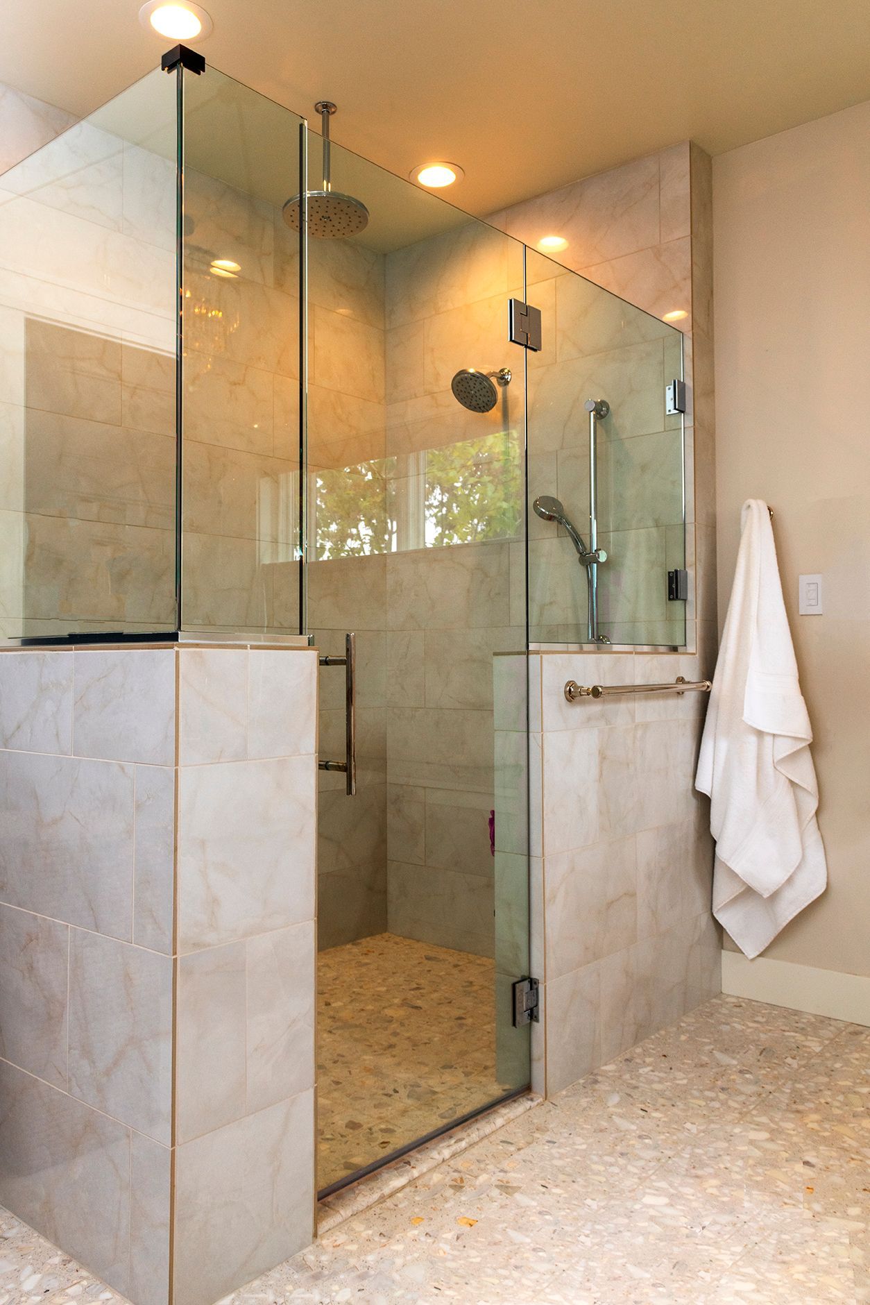 A bathroom with a walk in shower with a glass door.