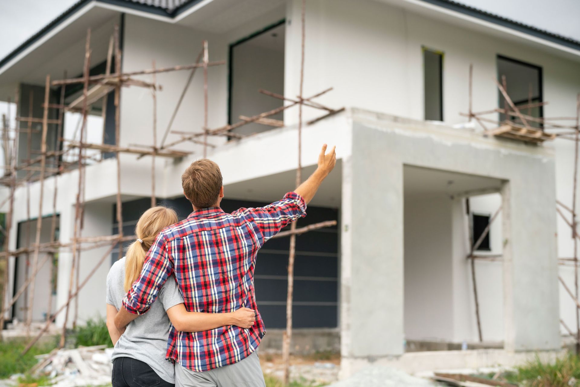 Young couple inspecting a house under construction for a custom home remodeling project.
