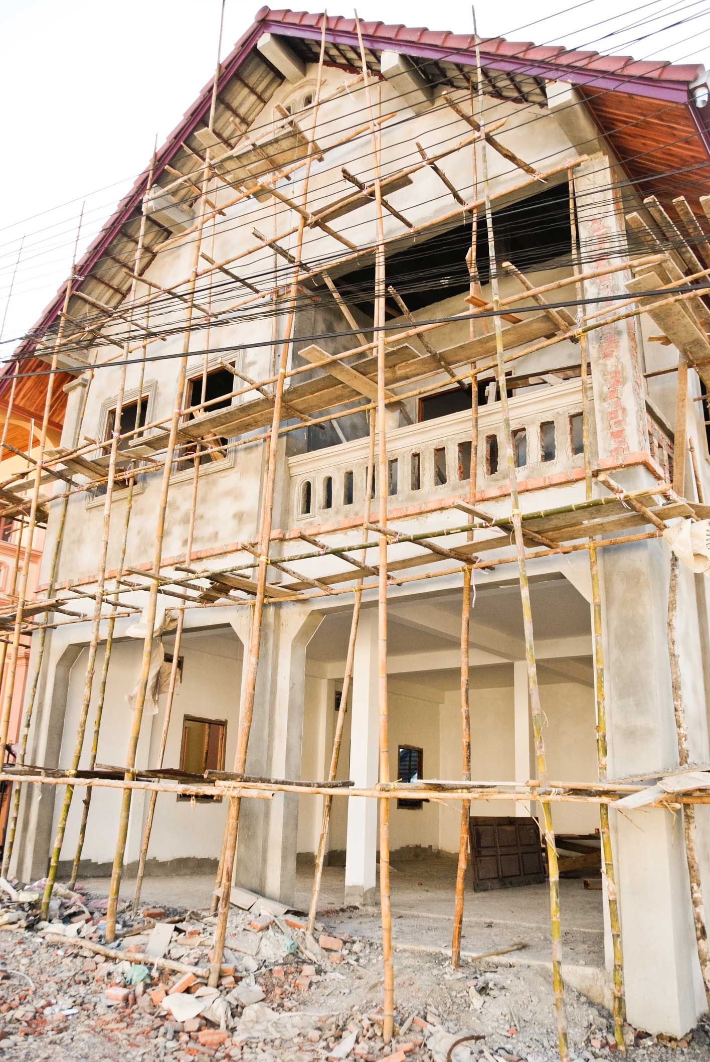House under construction with scaffolding, showcasing the stages of custom home remodeling.