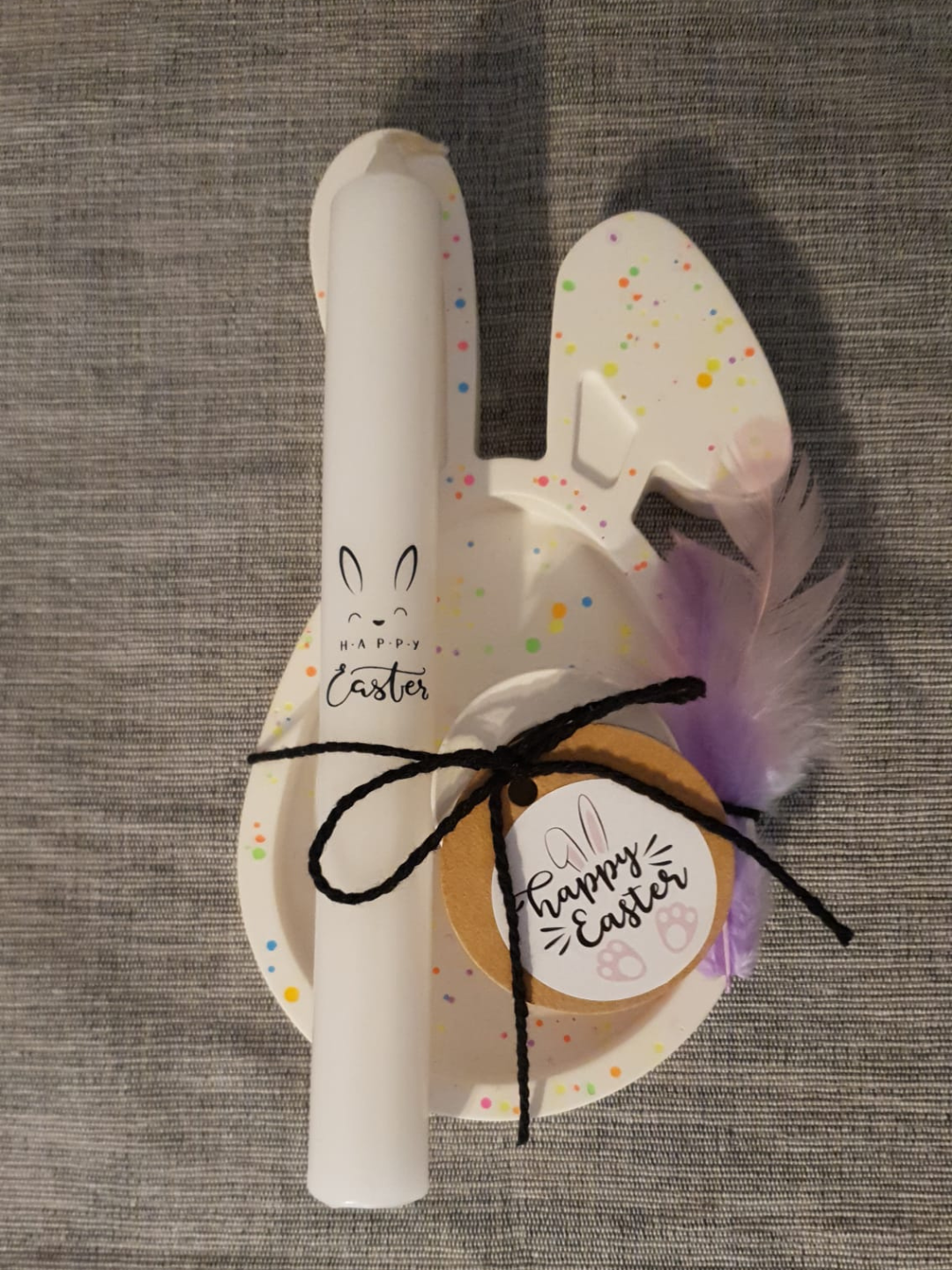 Décoration de lapin de Pâques blanc avec des éclaboussures de peinture pastel, une plume et un ruban noir.