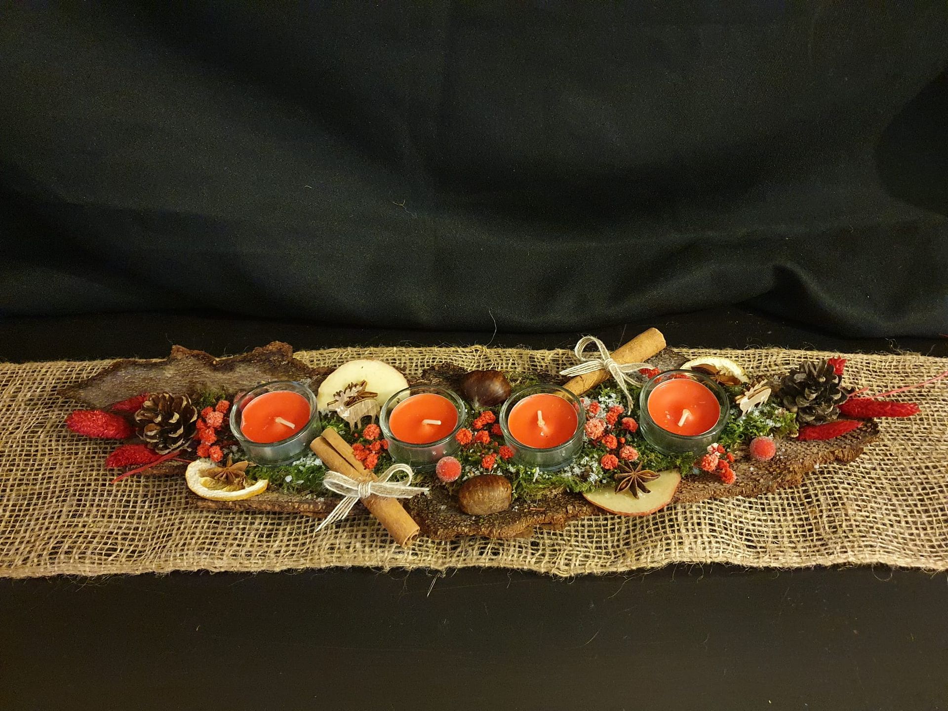 Chemin de table rustique en toile de jute avec un centre de table décoratif coloré composé de fleurs.