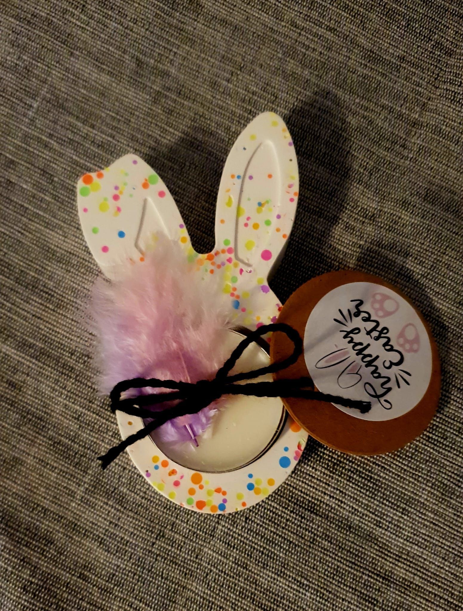 Carte décorée en forme de lapin avec un pompon rose duveteux et un nœud en ruban violet sur une surface texturée