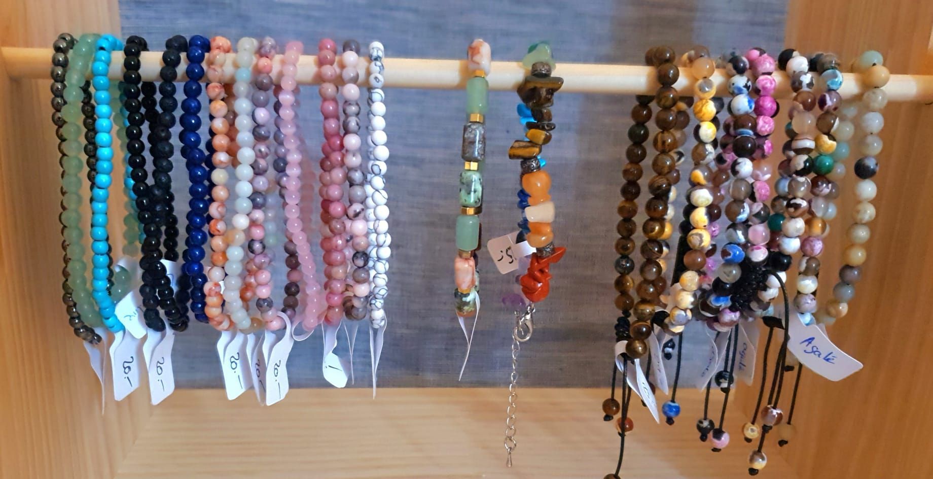 Bracelets et colliers de perles colorées suspendus à des chevilles en bois dans un étalage d'artisanat