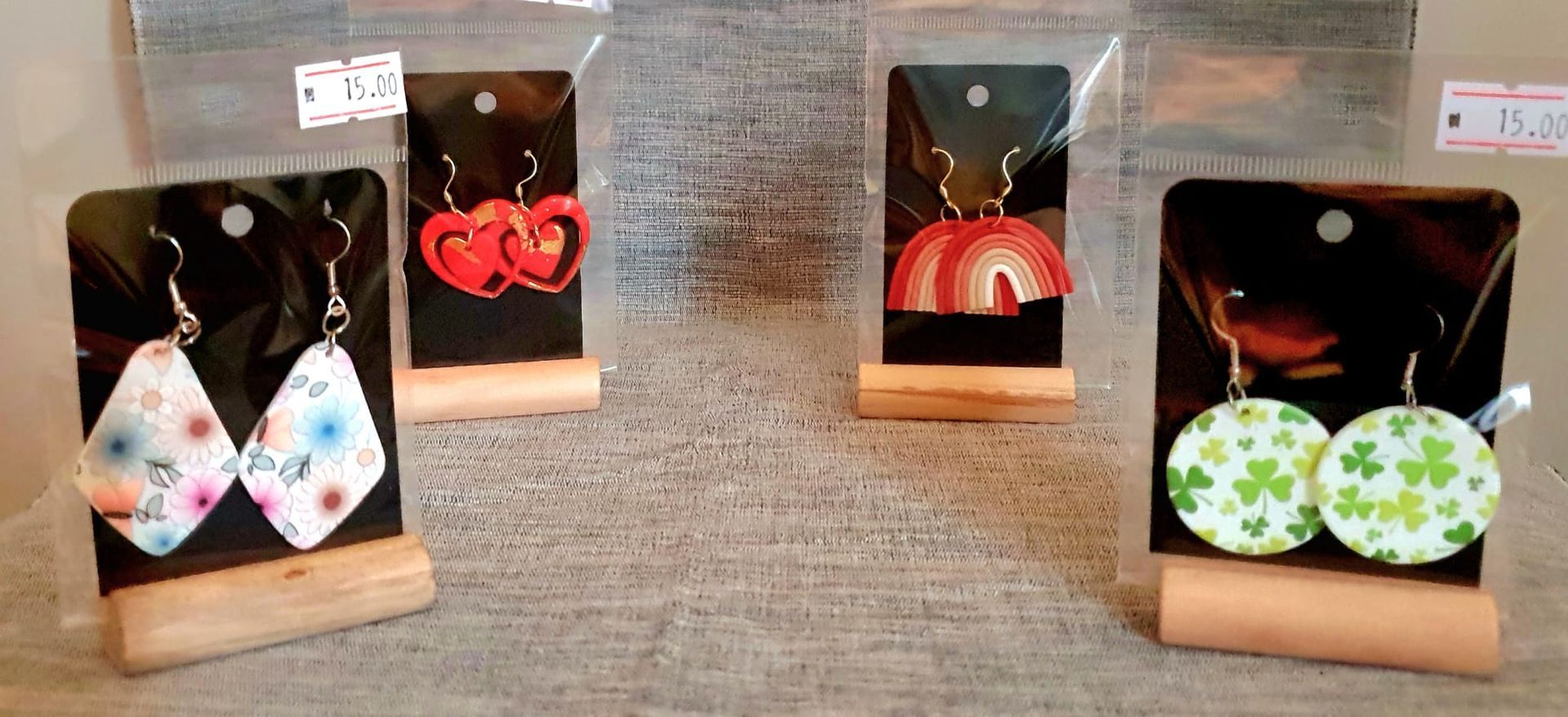 Boucles d'oreilles artisanales colorées assorties présentées sur de petits supports sur un fond gris texturé