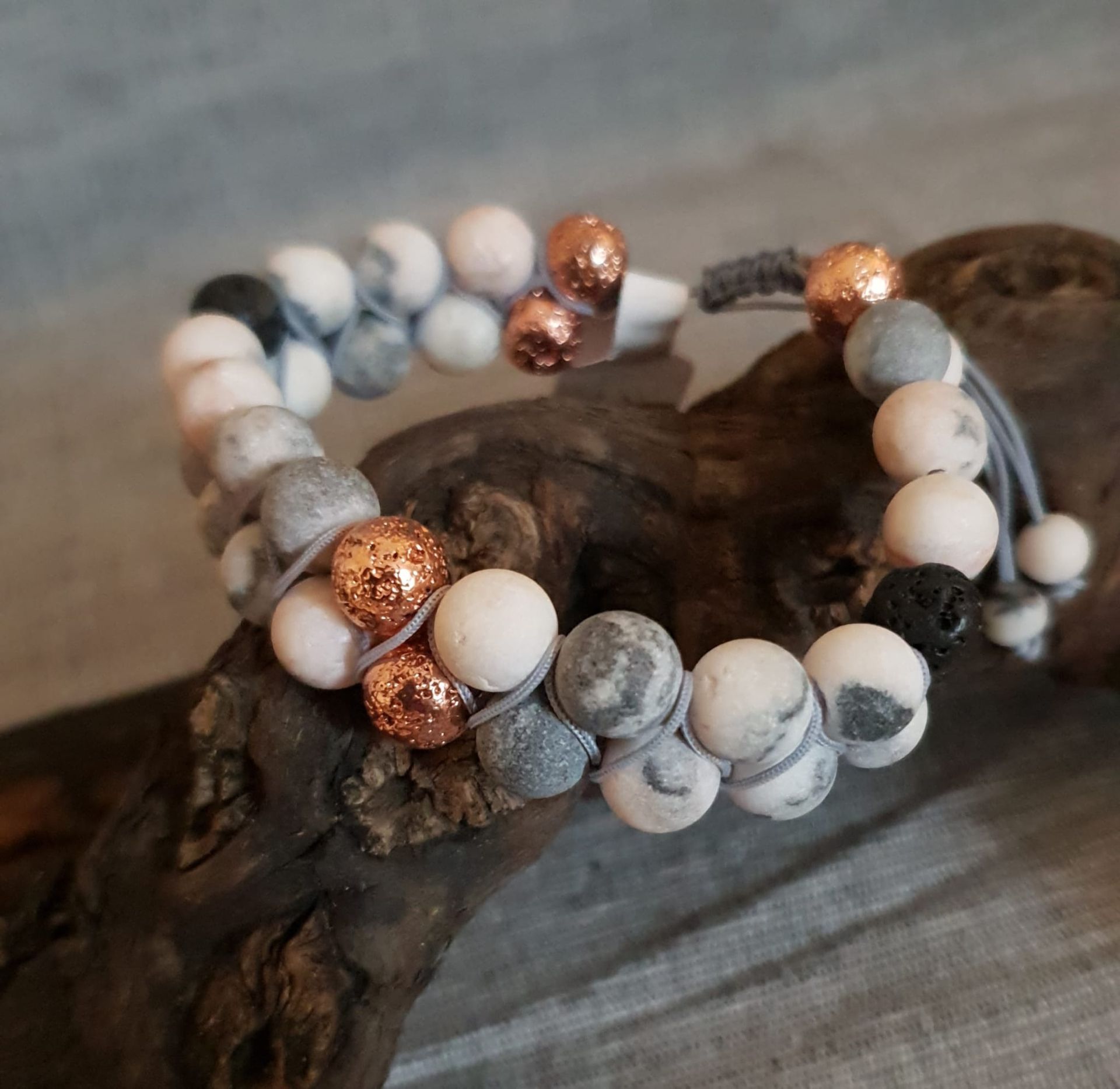 Bracelets en perles de marbre blanches, grises et cuivrées sur une surface en bois
