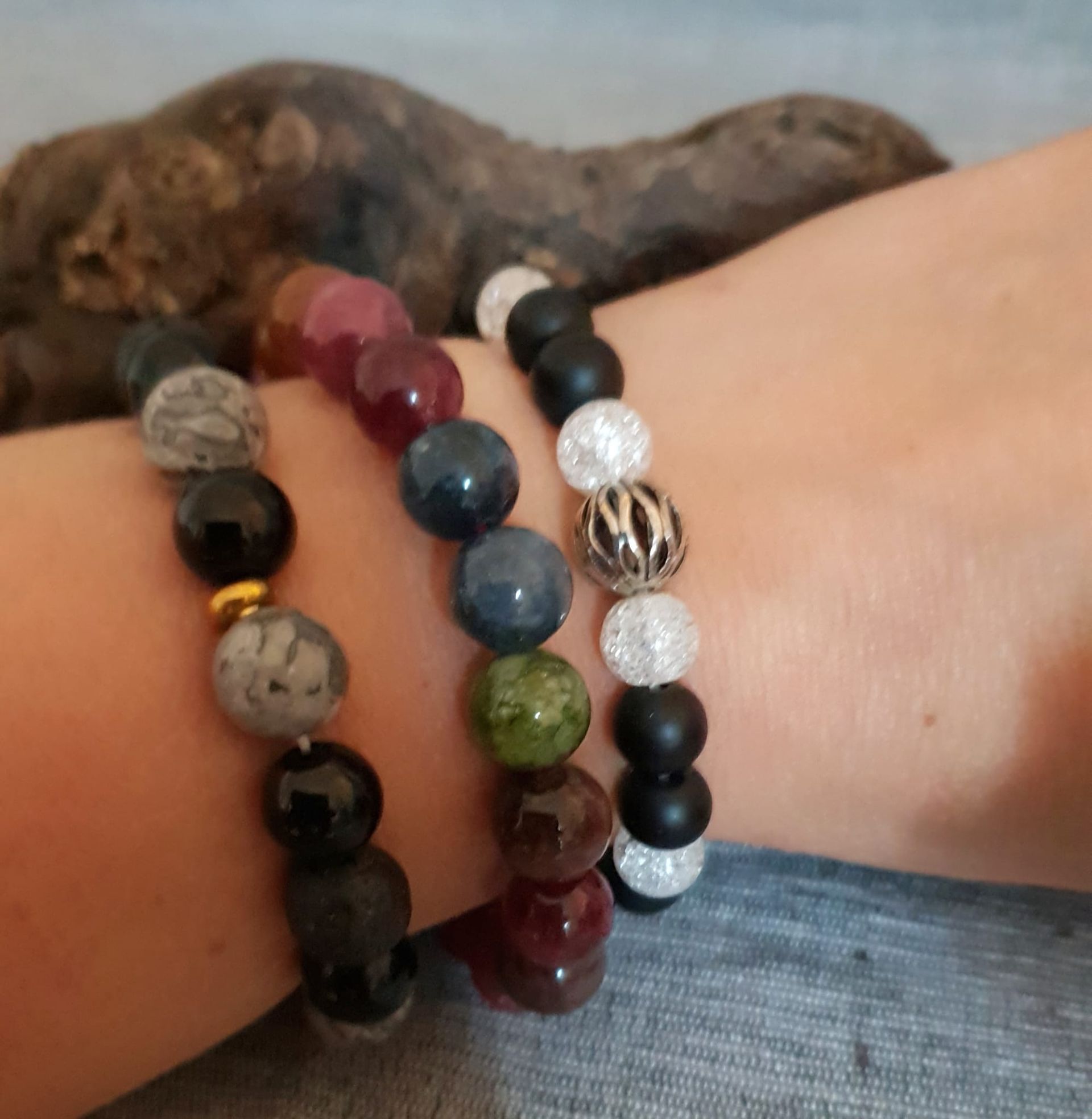 Poignet orné de quatre bracelets de perles noires, rouges, bleues, vertes et blanches sur un bras croisé