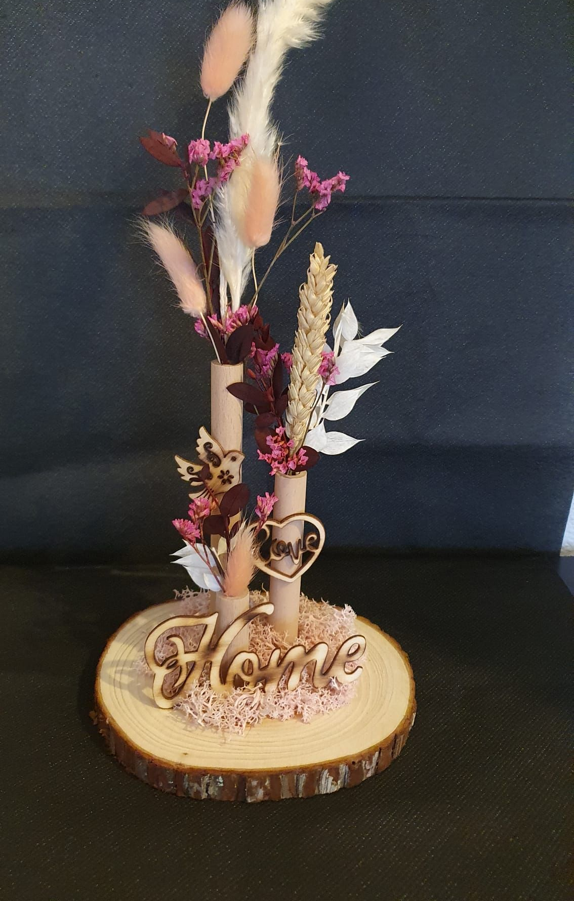 Composition florale séchée décorative sur un socle en rondelle de bois avec une inscription dorée « Fleur ».