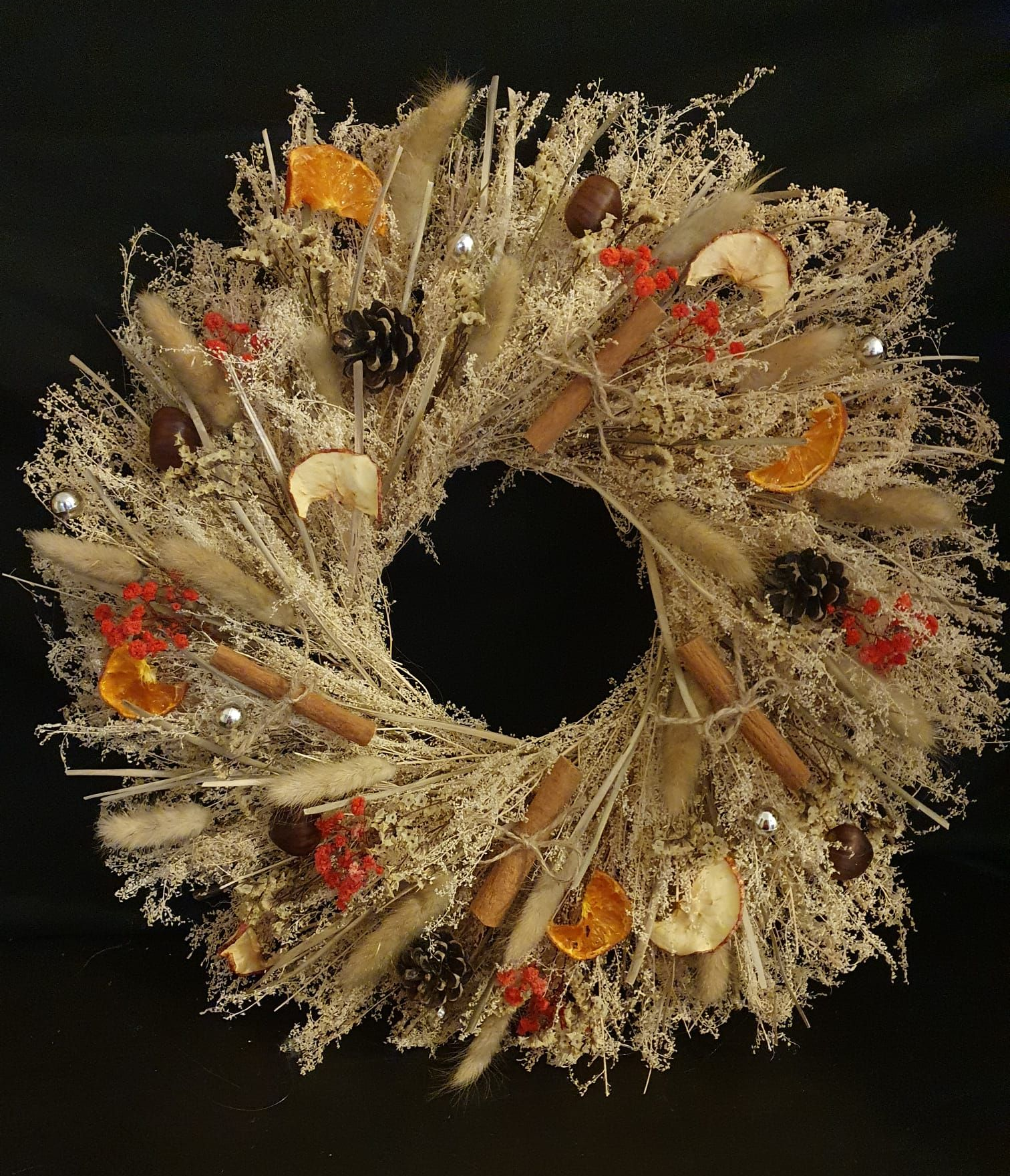 Couronne décorative beige avec pommes de pin, baies et feuilles d'automne sur fond noir