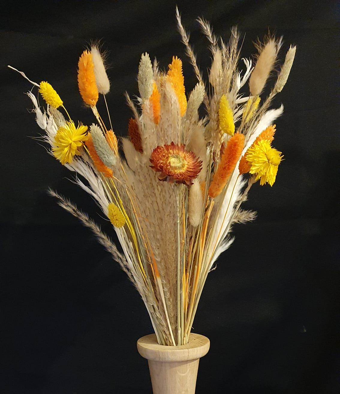 Bouquet de fleurs sauvages séchées dans un vase beige sur fond sombre