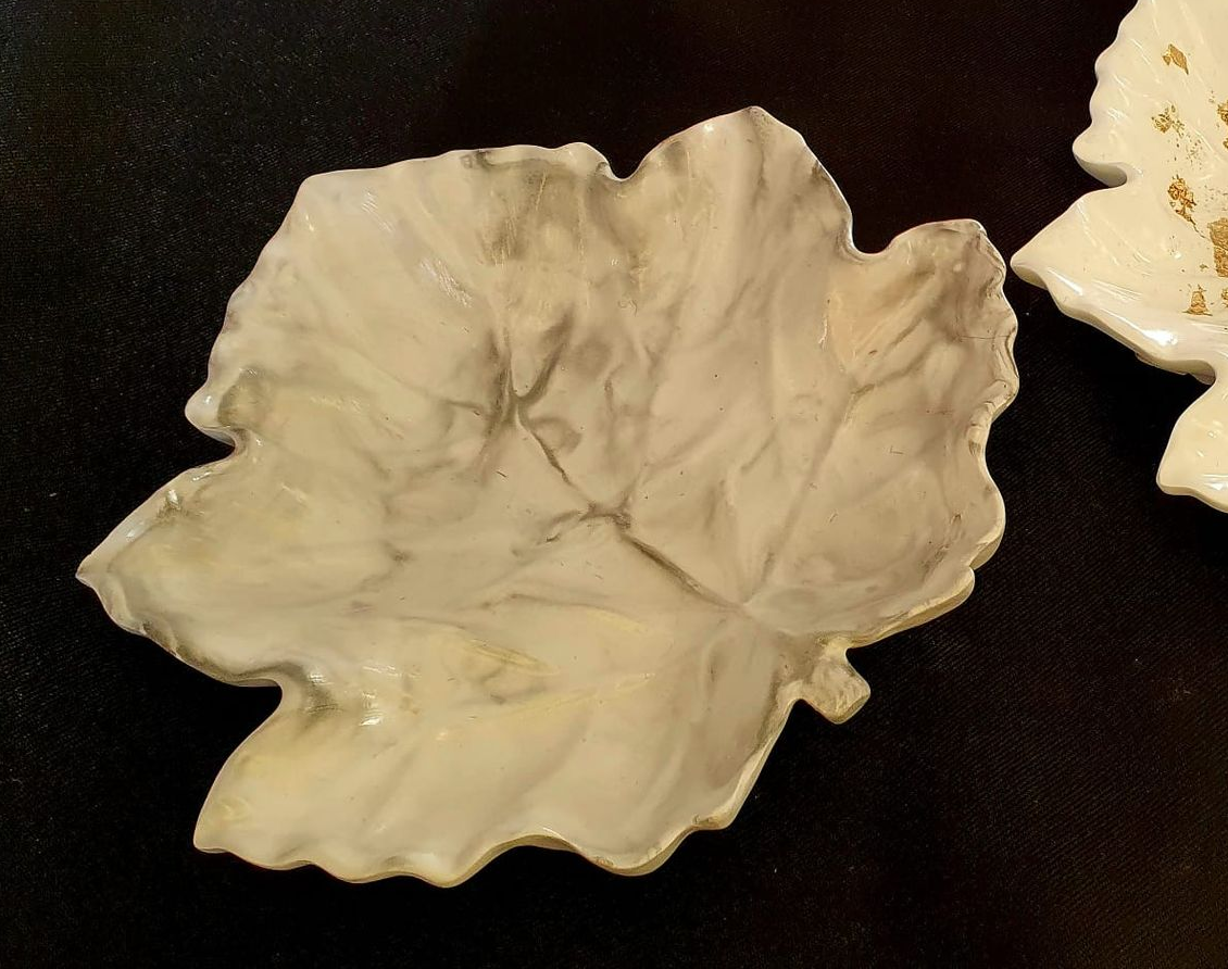 Plat en céramique couleur crème en forme de feuille sur fond noir.