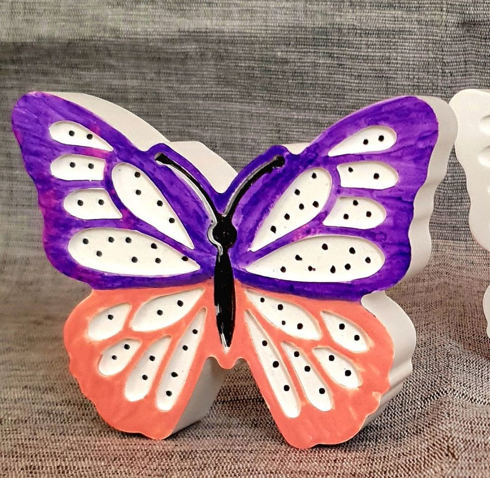 Décoration murale papillon violet et corail aux ailes blanches et à pois noirs sur fond gris texturé