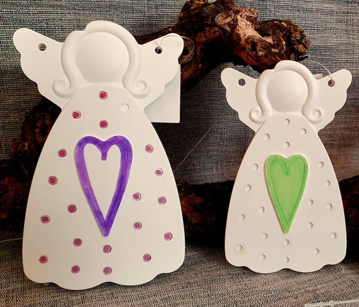 Deux ornements d'anges blancs avec des détails de cœurs violets et verts sur un fond gris texturé