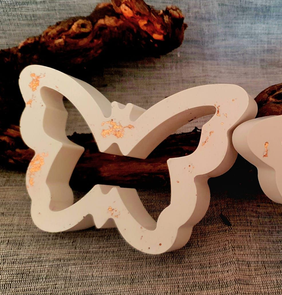 Découpe décorative en forme de papillon blanc sur fond de tissu marron avec des brindilles séchées.
