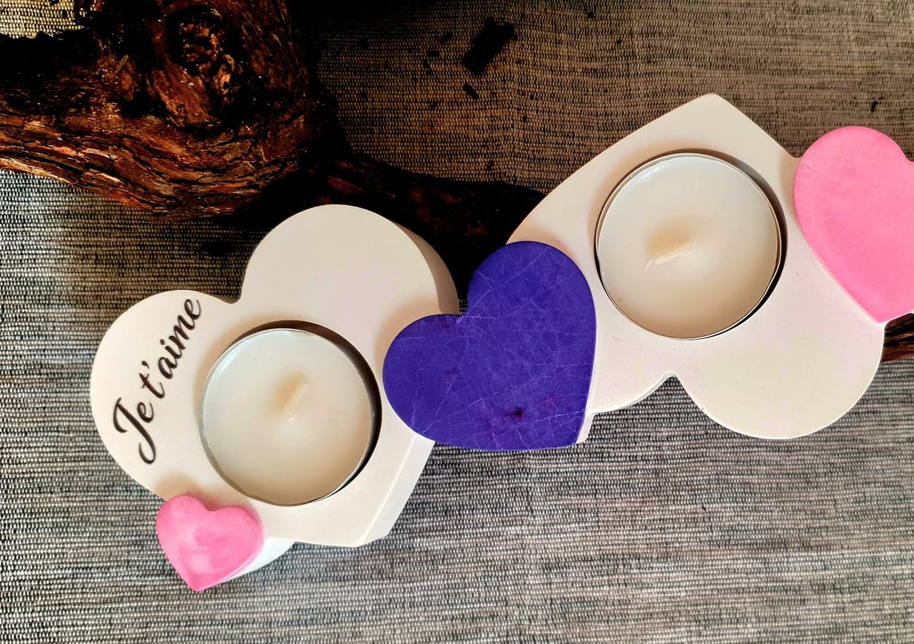 Bougeoirs en forme de cœur avec des cœurs en feutre rose et violet sur une surface en tissu texturé