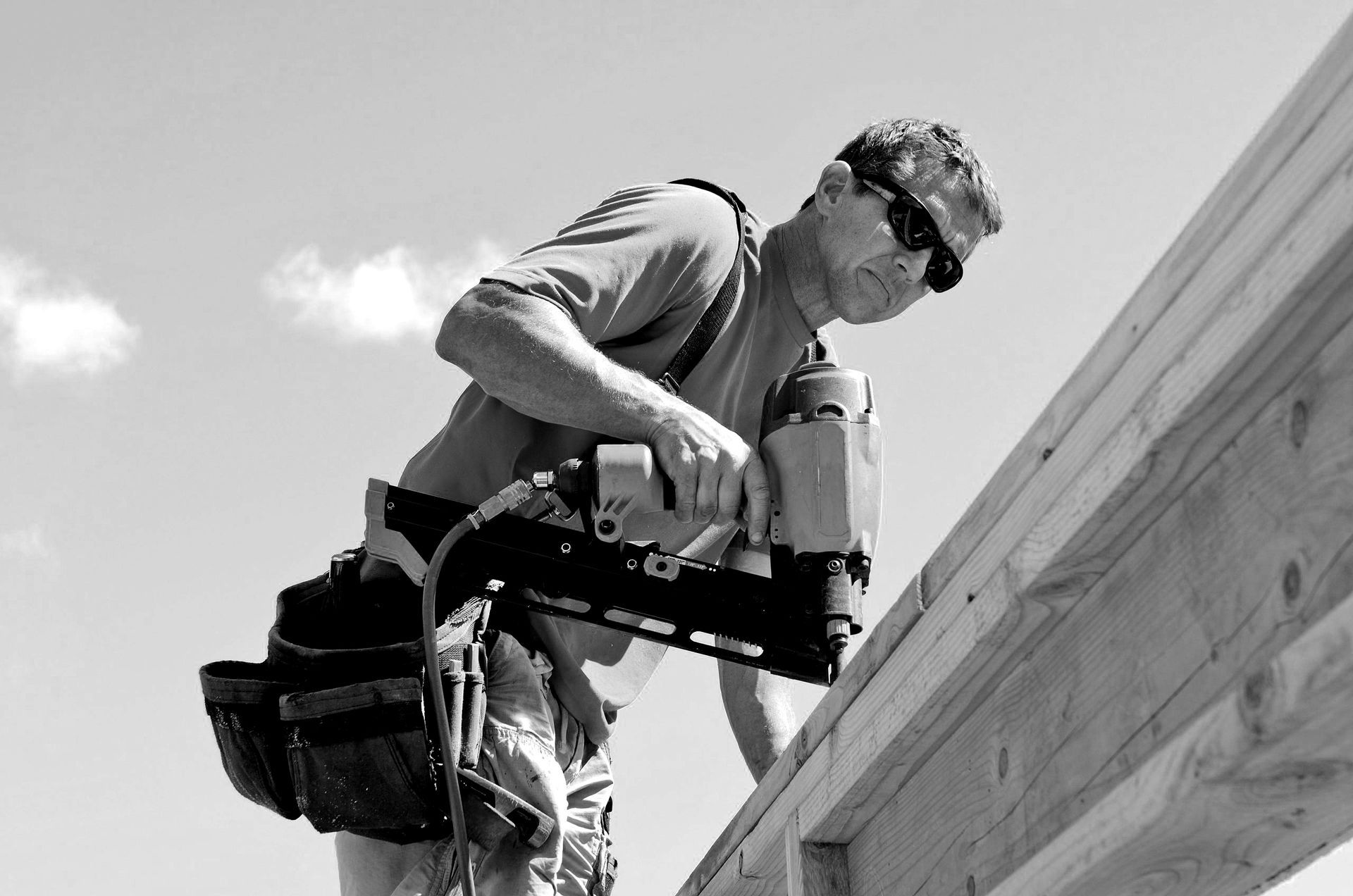 Worker using a power drill on a roof edge, using Framer's Choice Nails.