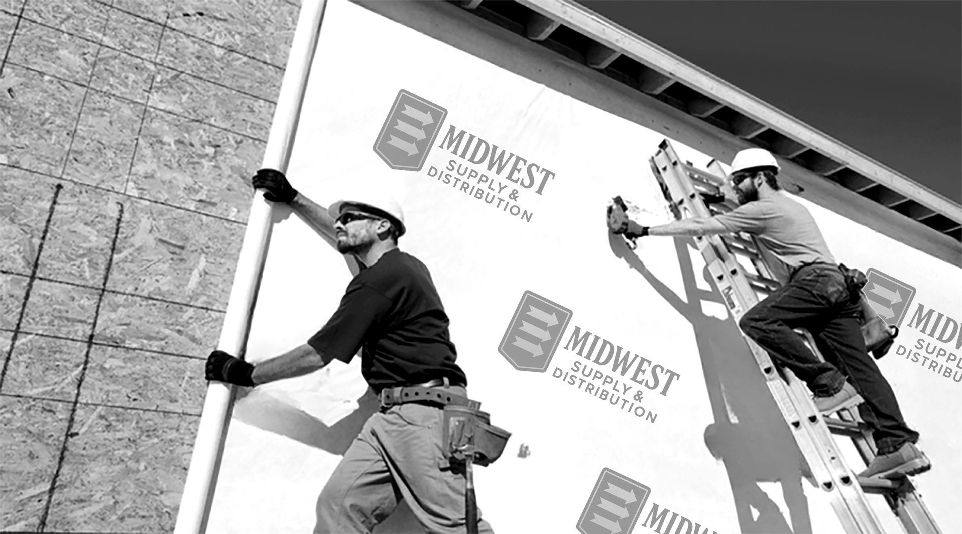 Two workers install exterior house wrap from Midwest Supply & Distribution.