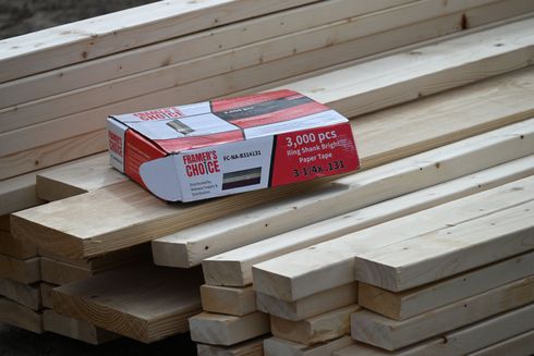 Stacks of wooden boards with a red-and-white box of nails on top