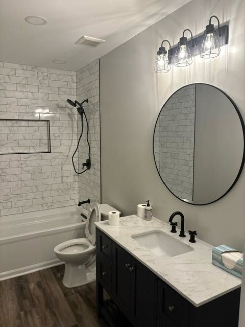 Modern bathroom with white subway tile, black vanity, oval mirror, and bathtub.