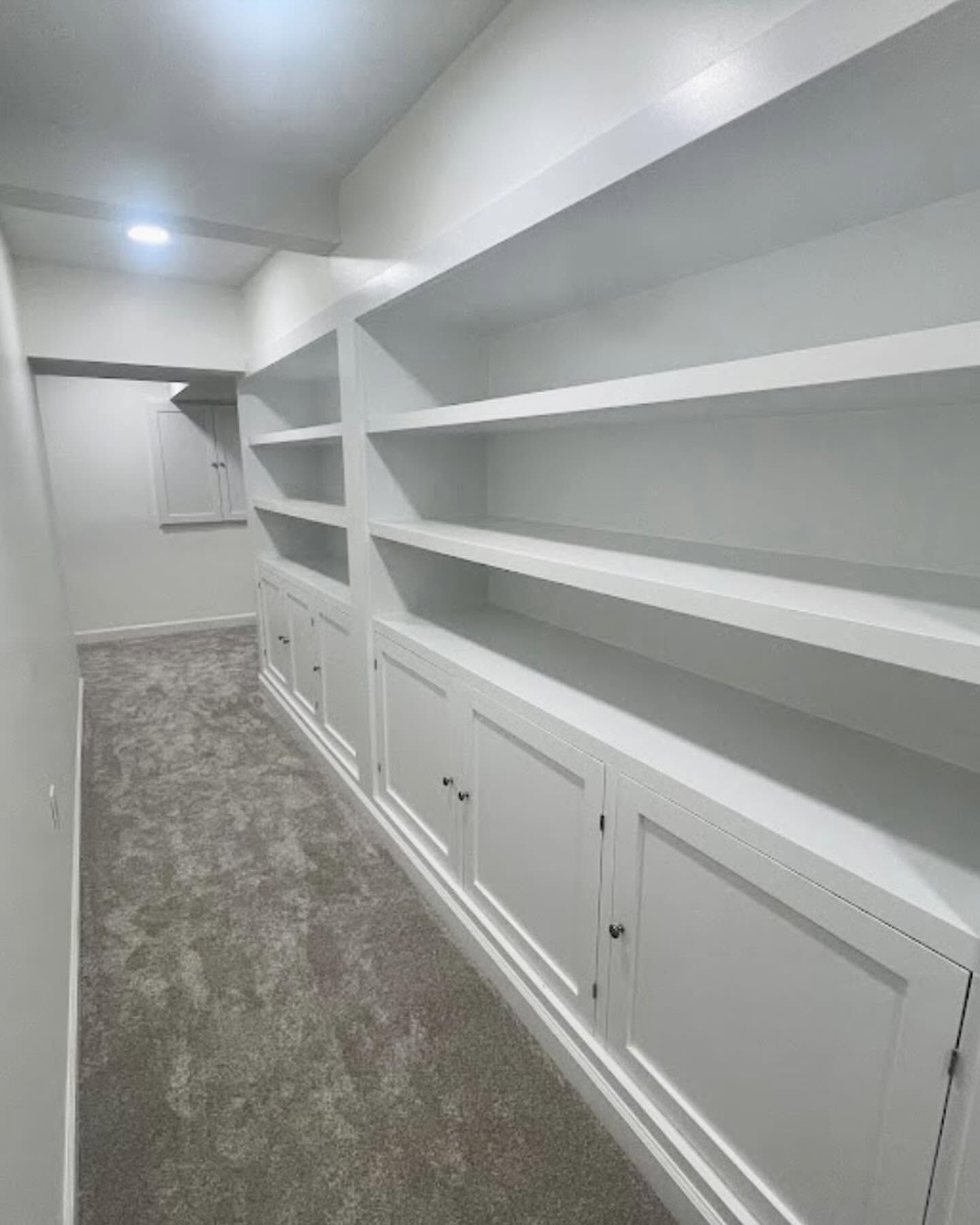 White walk-in closet with built-in shelves, cabinets, and carpeted floor.