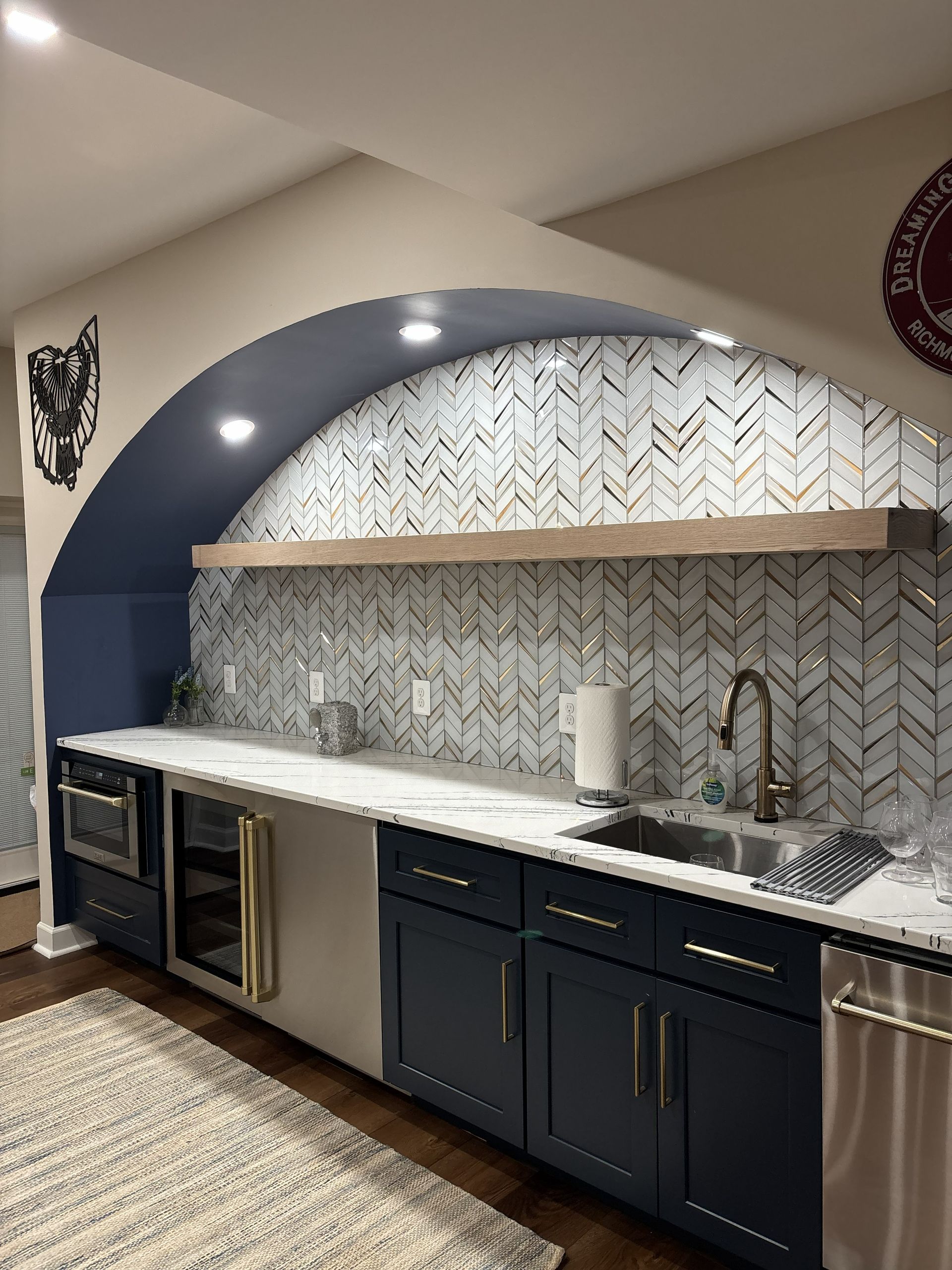 Modern kitchen with arched blue alcove, patterned tile backsplash, white countertop, and dark cabinets