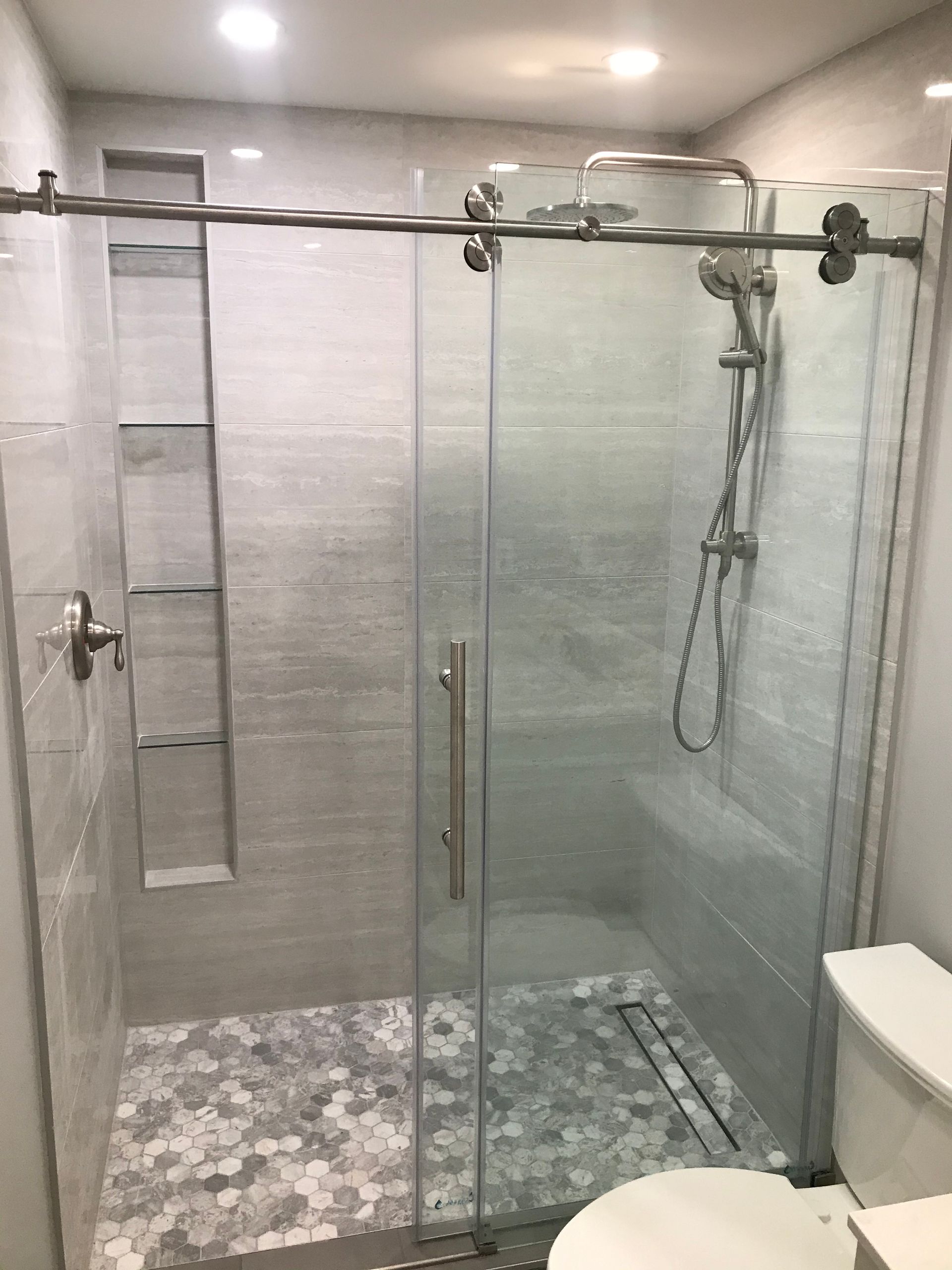 Modern tiled bathroom with a glass walk-in shower and handheld showerhead