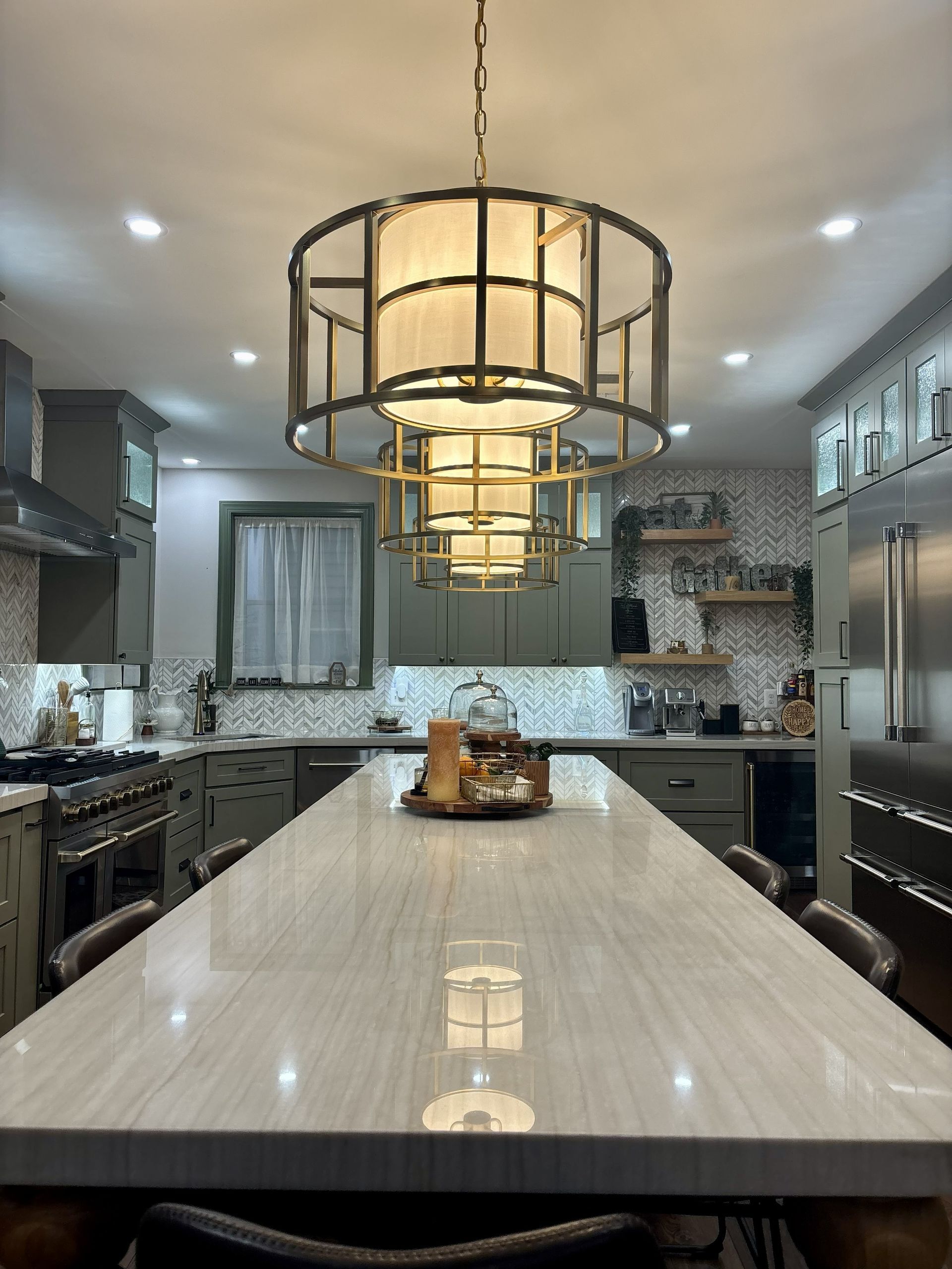 Modern kitchen with a long marble island and large pendant lights overhead.