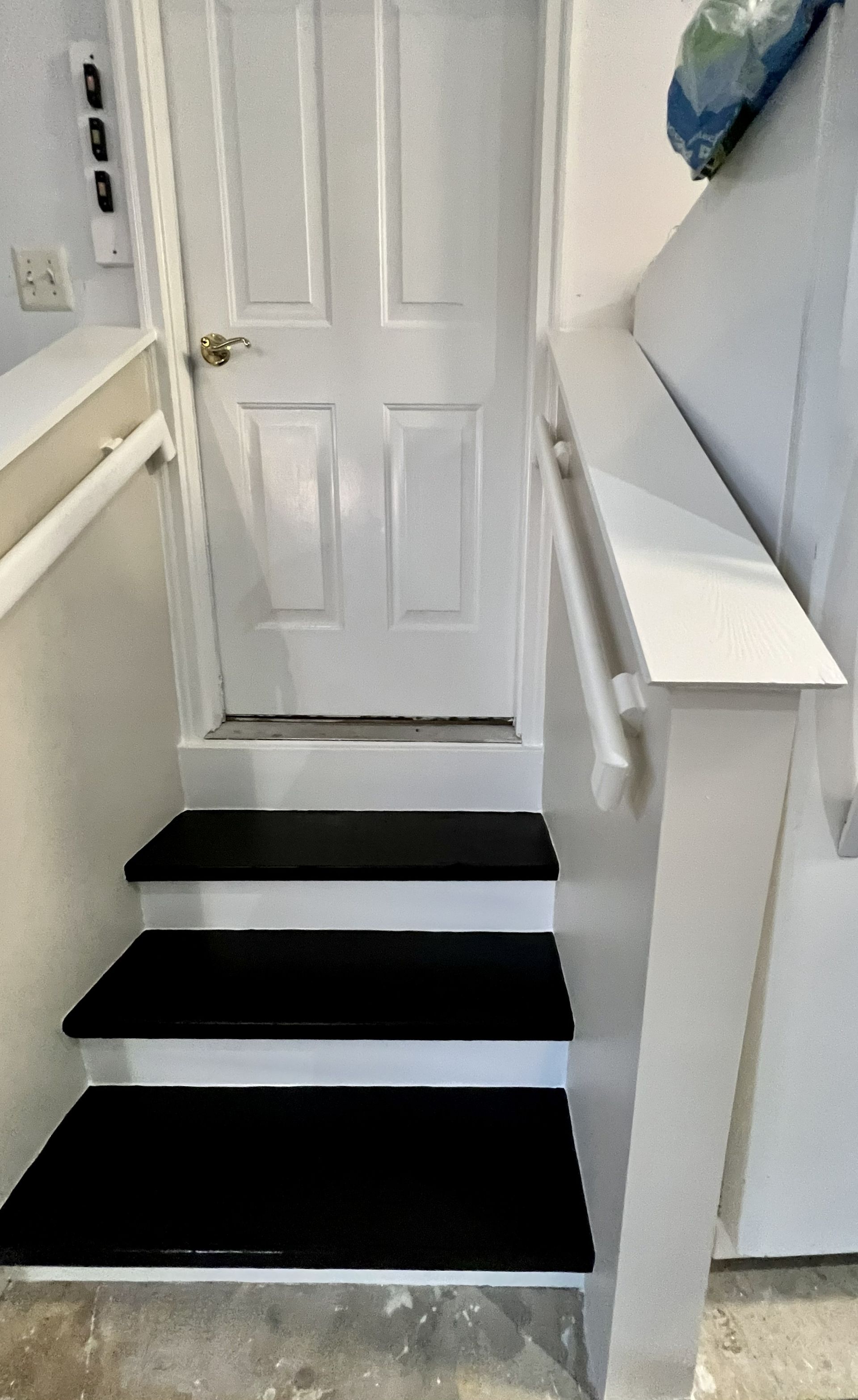 Narrow indoor staircase with black-and-white steps leading to a closed white door