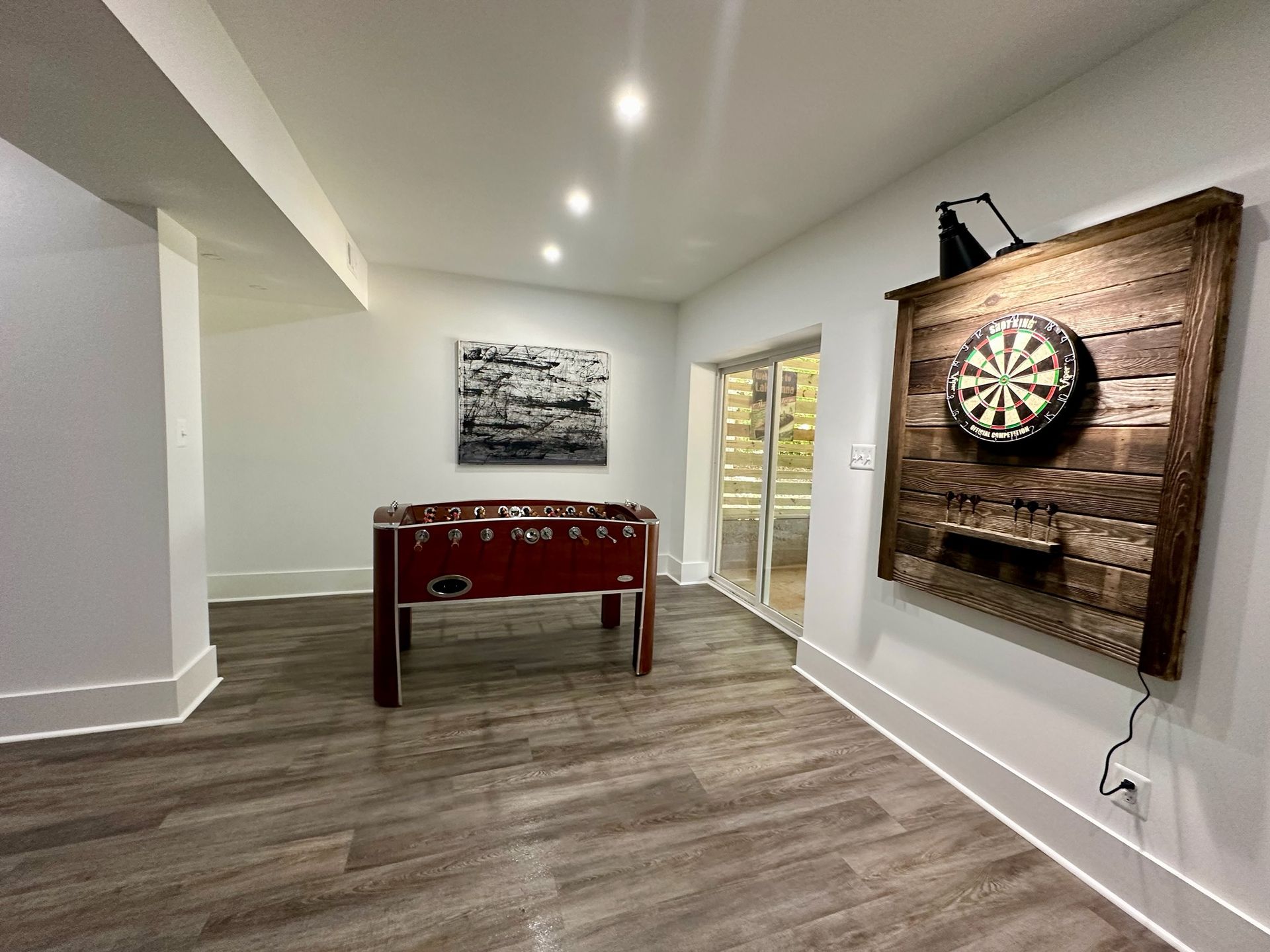 Basement rec room with foosball table and dartboard on a wood accent wall