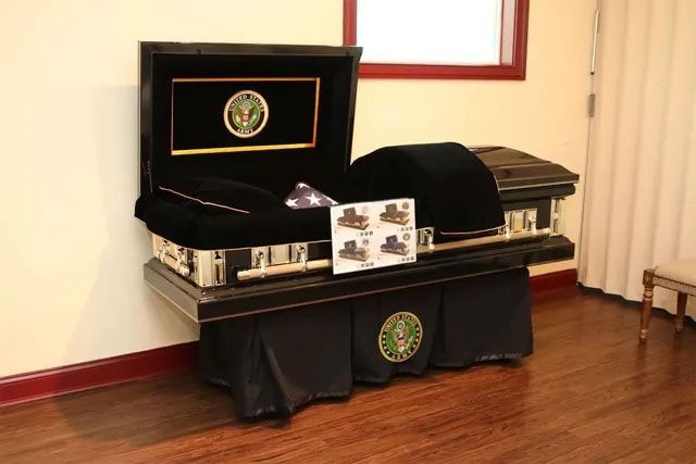 A black coffin is sitting on a wooden floor in a room.