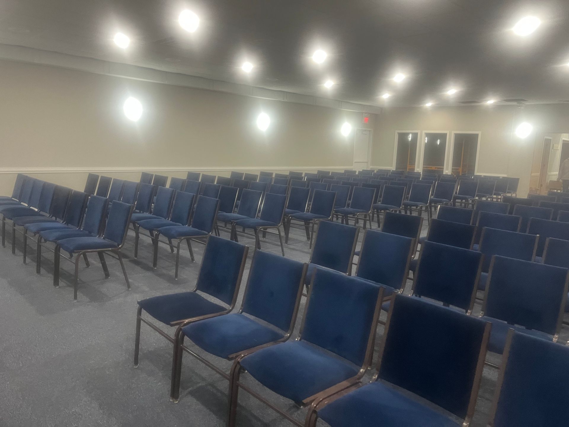 Empty conference room with rows of blue chairs under bright ceiling lights