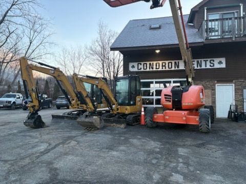 Construction equipment parked outside a rental business with a gray sky.